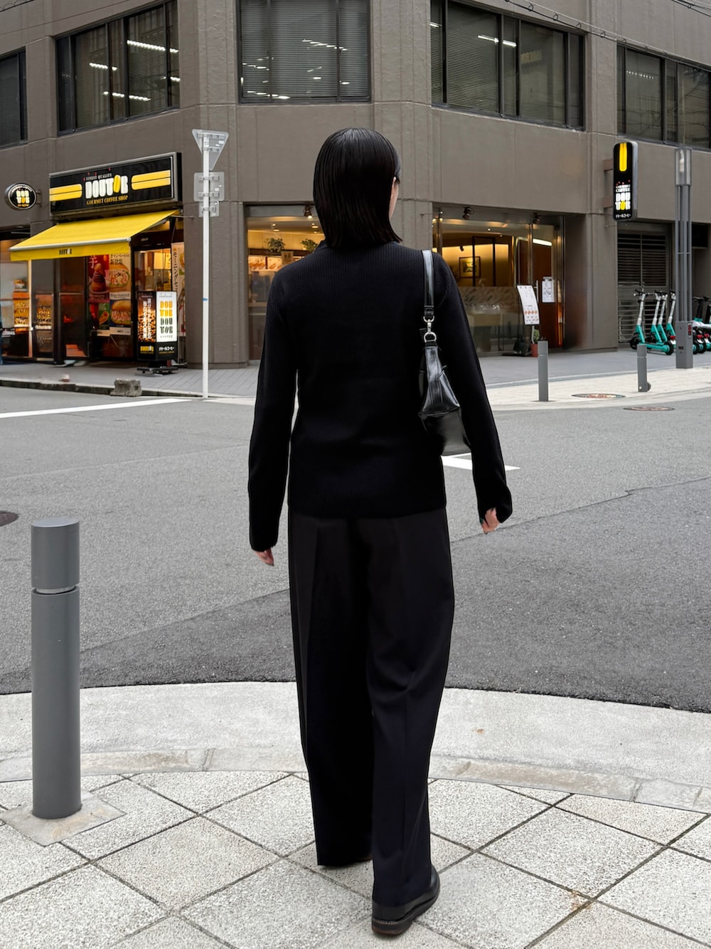 ブラック系のニット/セーター、ブラック系のスラックス、ブラック系のショルダーバッグを着用したレディースの秋コーディネートの4枚目の写真