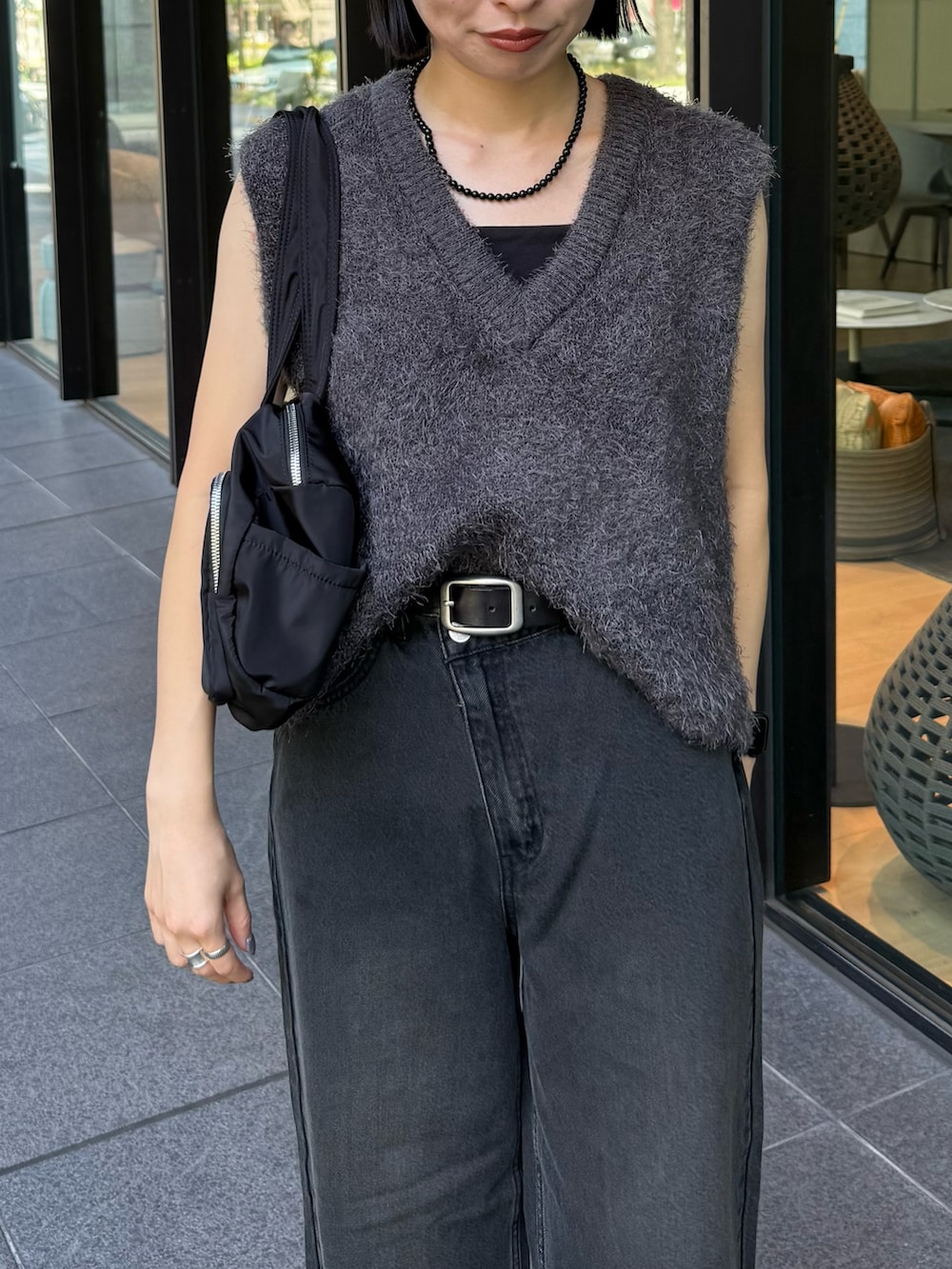 グレー系のベスト、ブラック系のデニムパンツを着用したレディースの秋コーディネートの2枚目の写真