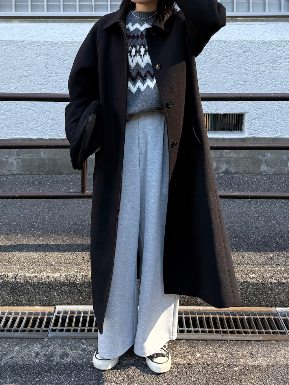 グレー系のパンツ、ブラック系のステンカラーコート、グレー系のニット/セーターを着用したレディースの冬コーディネートの2枚目の写真