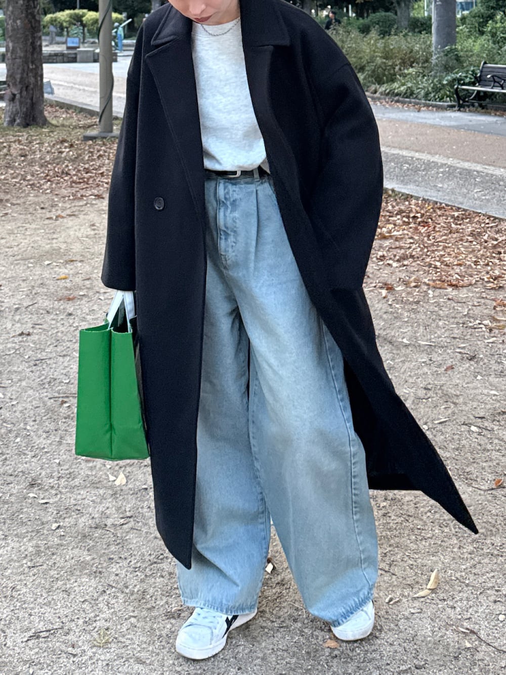 ブラック系のチェスターコート、グレー系のTシャツ/カットソー、ブルー系のデニムパンツを着用したレディースの冬コーディネートの2枚目の写真