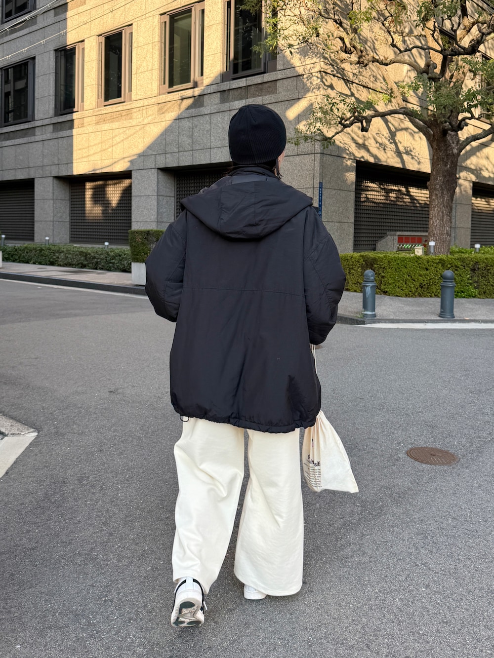 ブラック系のダウンジャケット/コート、ホワイト系のTシャツ/カットソー、ホワイト系のその他パンツを着用したレディースの秋コーディネートの4枚目の写真