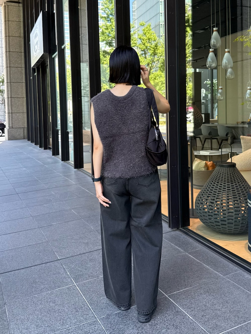 グレー系のベスト、ブラック系のデニムパンツを着用したレディースの秋コーディネートの4枚目の写真