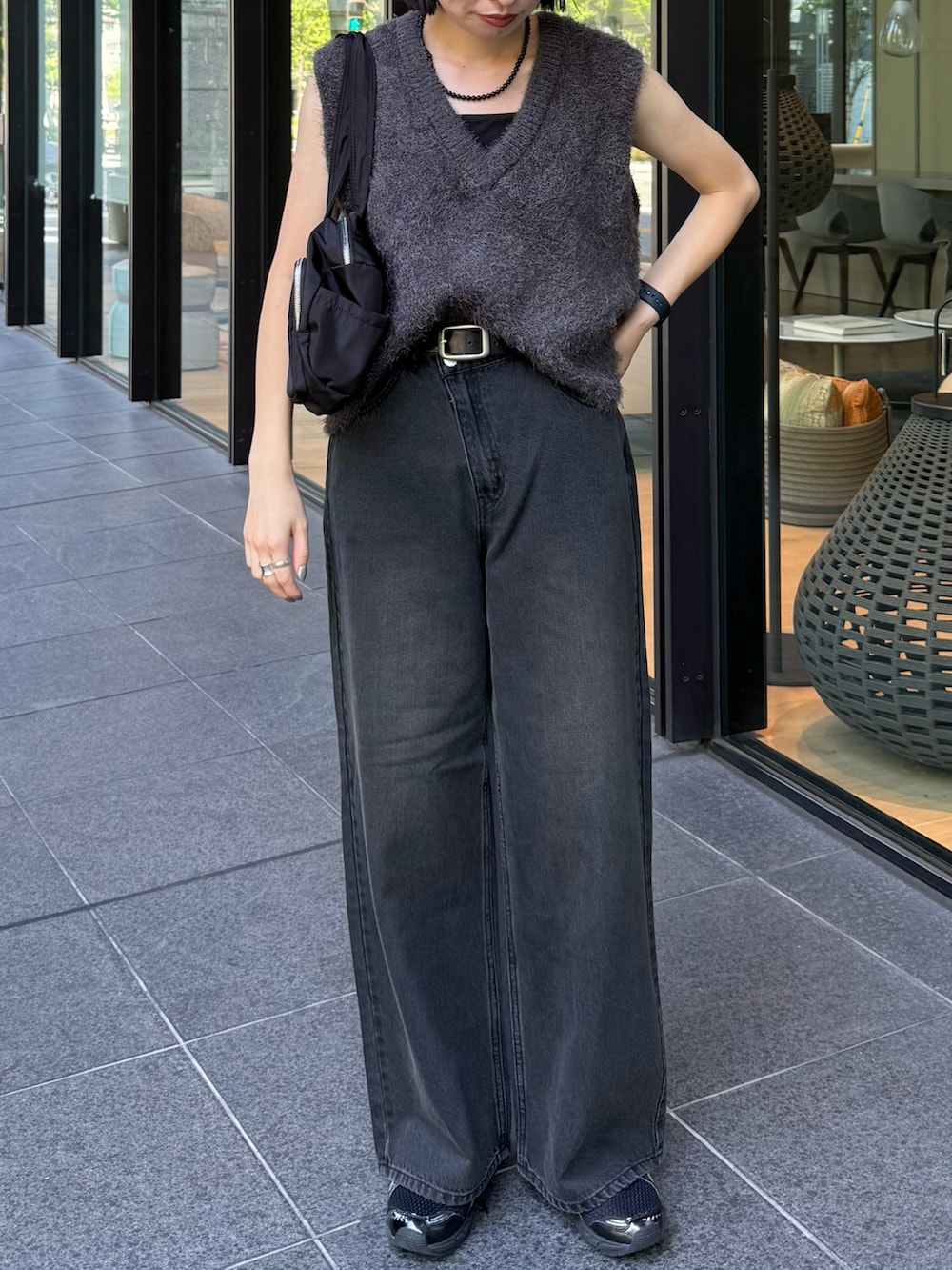 グレー系のベスト、ブラック系のデニムパンツを着用したレディースの秋コーディネートの3枚目の写真