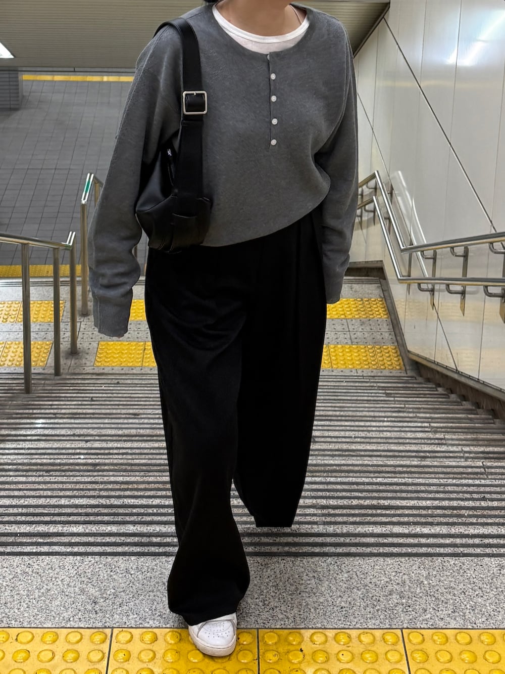 グレー系のニット/セーター、ブラック系のTシャツ/カットソー、ブラック系のショルダーバッグを着用したレディースの秋コーディネートの4枚目の写真