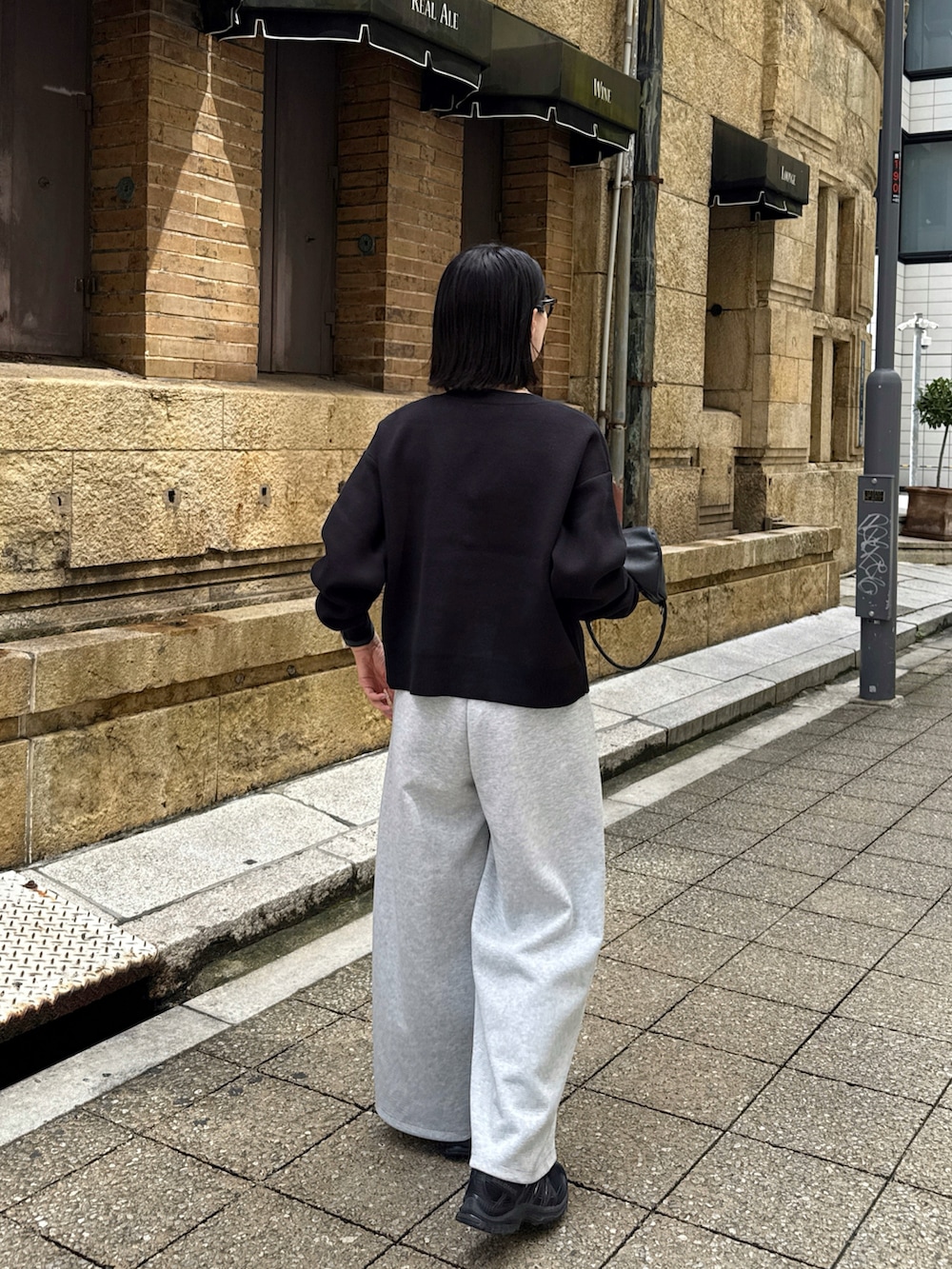 ブラック系のカーディガン/ボレロ、グレー系のパンツ、ブラック系のショルダーバッグを着用したレディースの秋コーディネートの4枚目の写真