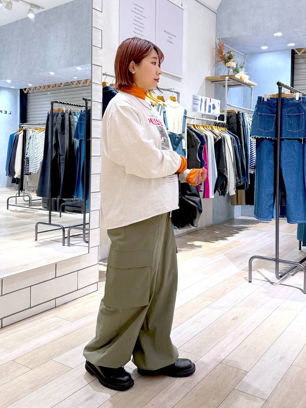 ブラック系のショルダーバッグ、オレンジ系のニット/セーター、グリーン系のカーゴパンツを着用したレディースの冬コーディネートの3枚目の写真