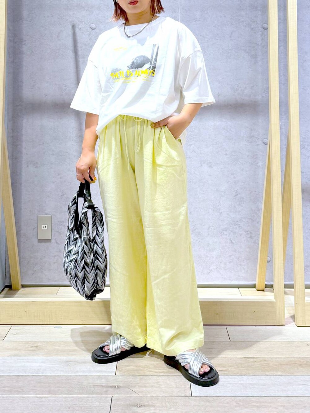 ブラック系のハンドバッグ、イエロー系のその他パンツ、シルバー系のサンダルを着用したレディースの夏コーディネートの2枚目の写真