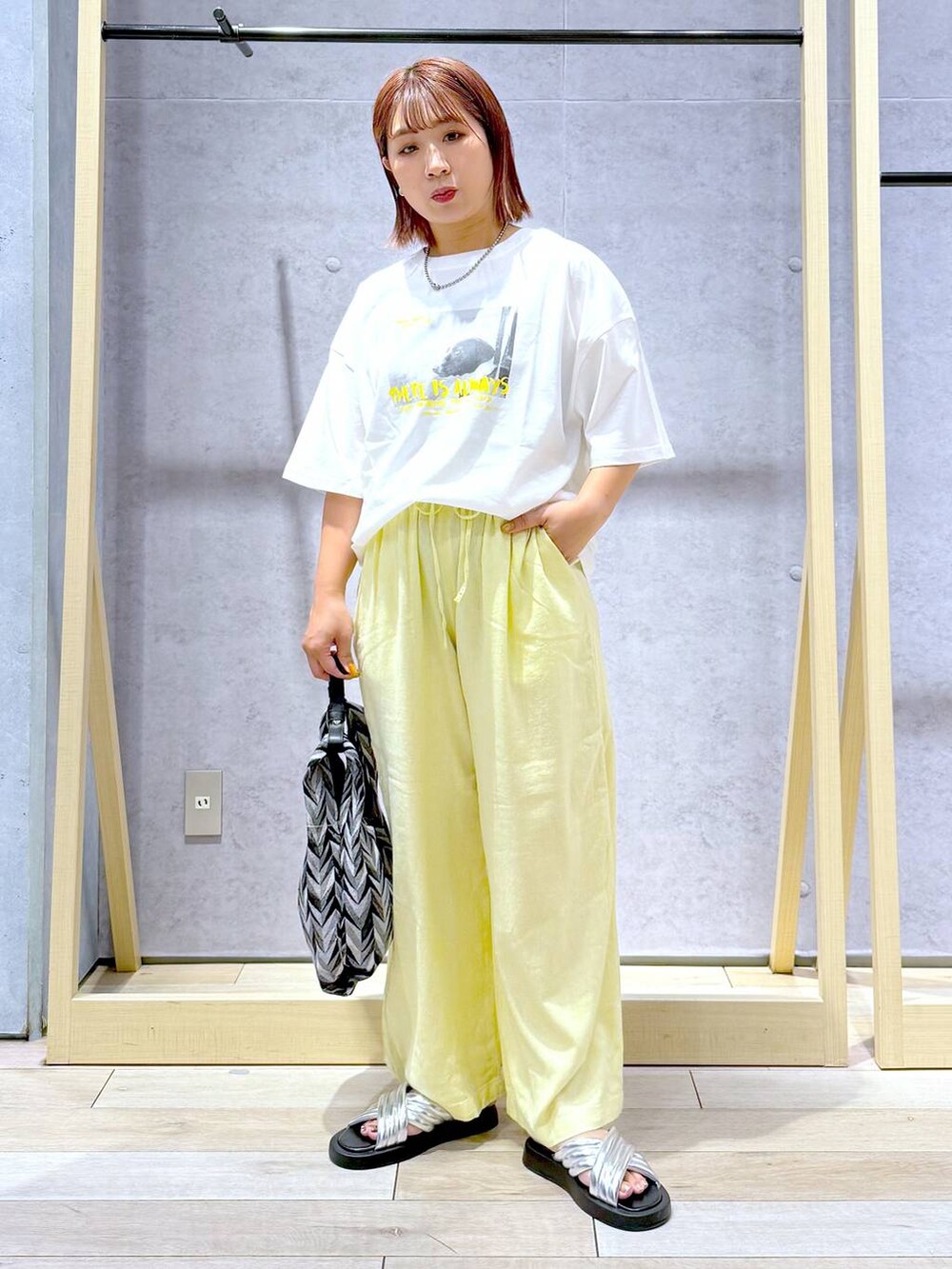 ブラック系のハンドバッグ、イエロー系のその他パンツ、シルバー系のサンダルを着用したレディースの夏コーディネートの7枚目の写真