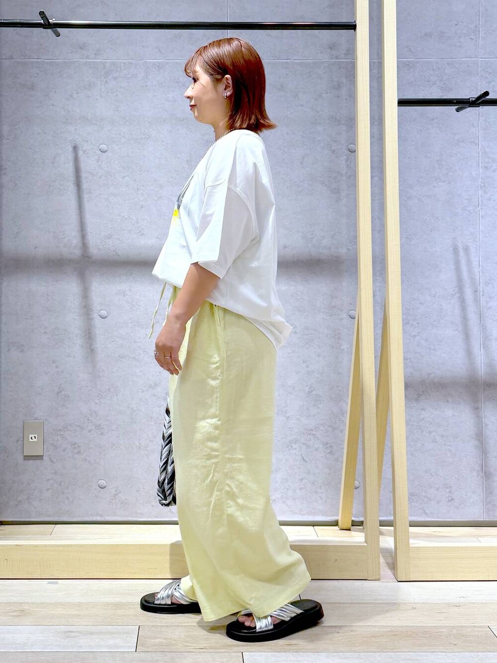 ブラック系のハンドバッグ、イエロー系のその他パンツ、シルバー系のサンダルを着用したレディースの夏コーディネートの5枚目の写真