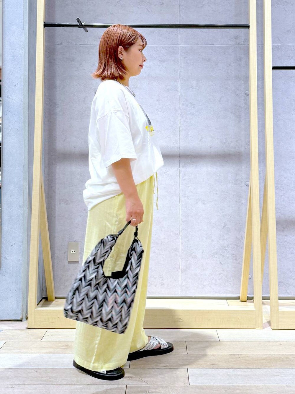 ブラック系のハンドバッグ、イエロー系のその他パンツ、シルバー系のサンダルを着用したレディースの夏コーディネートの3枚目の写真