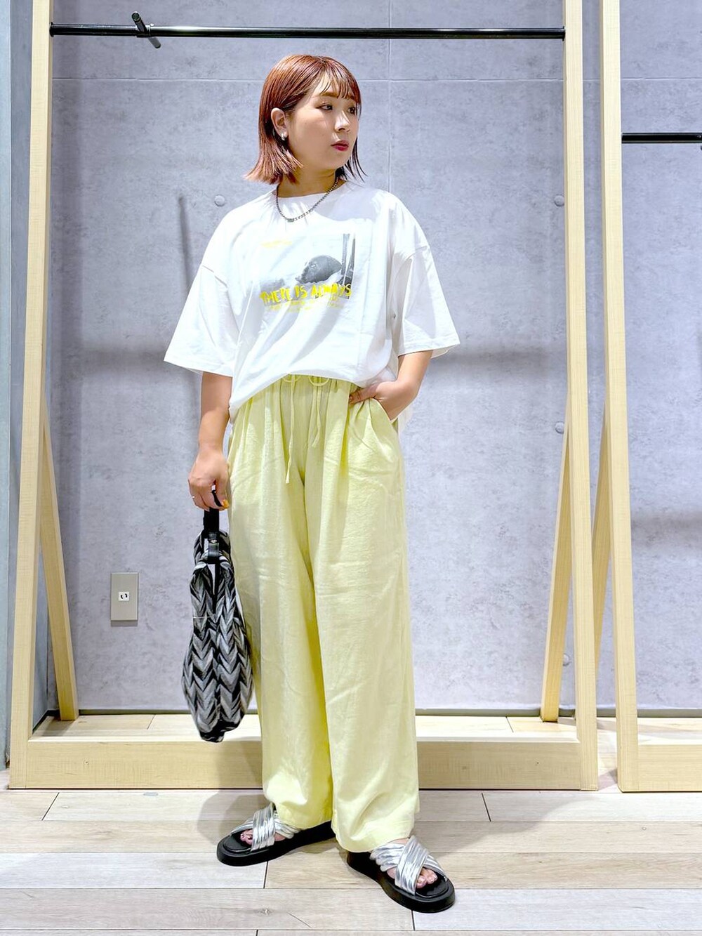 ブラック系のハンドバッグ、イエロー系のその他パンツ、シルバー系のサンダルを着用したレディースの夏コーディネートの8枚目の写真