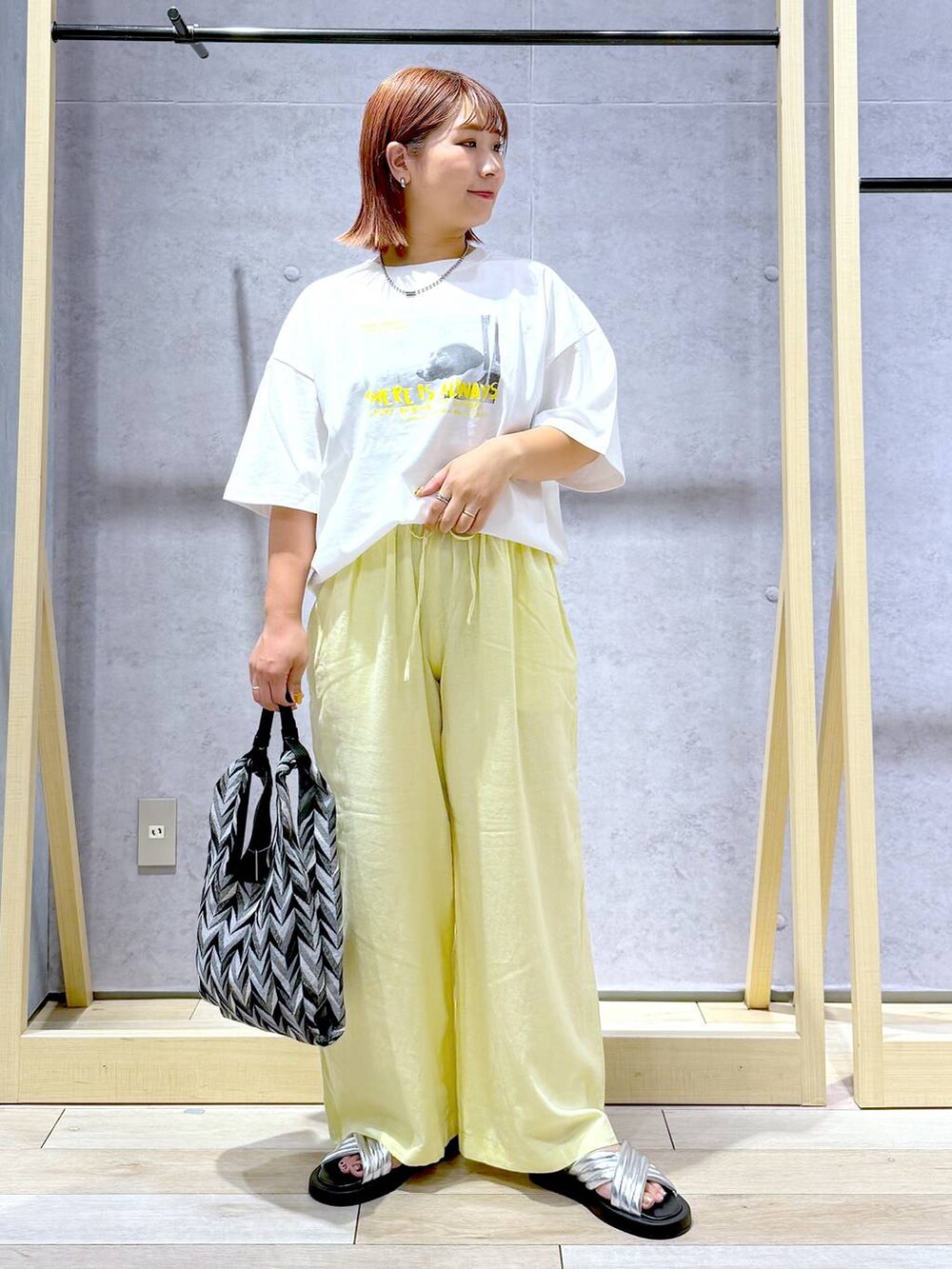 ブラック系のハンドバッグ、イエロー系のその他パンツ、シルバー系のサンダルを着用したレディースの夏コーディネートの6枚目の写真