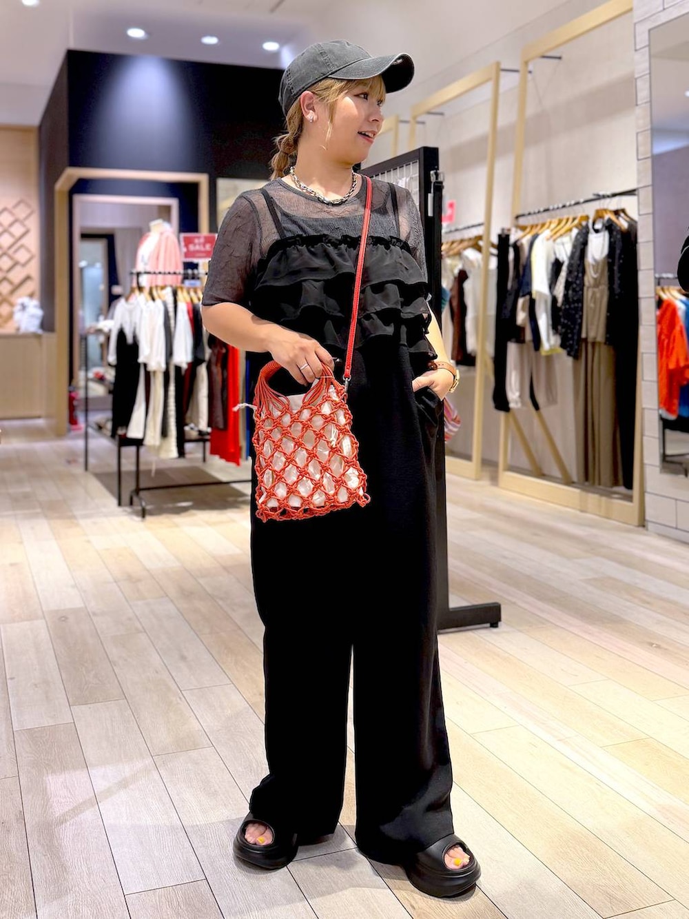 オレンジ系のハンドバッグ、ブラック系のサンダル、グレー系のTシャツ/カットソーを着用したレディースの夏コーディネートの6枚目の写真