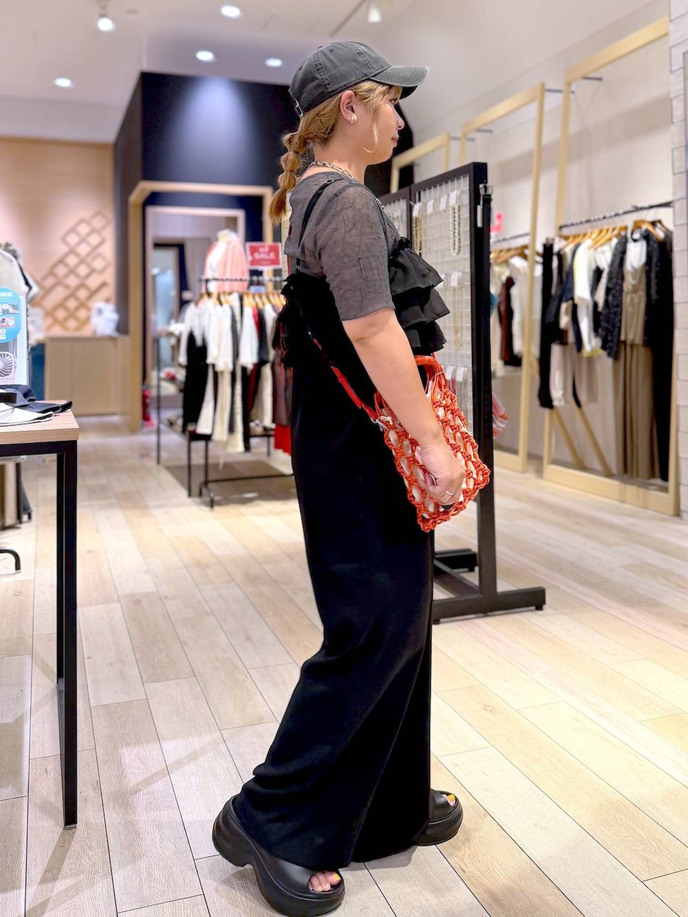 オレンジ系のハンドバッグ、ブラック系のサンダル、グレー系のTシャツ/カットソーを着用したレディースの夏コーディネートの3枚目の写真