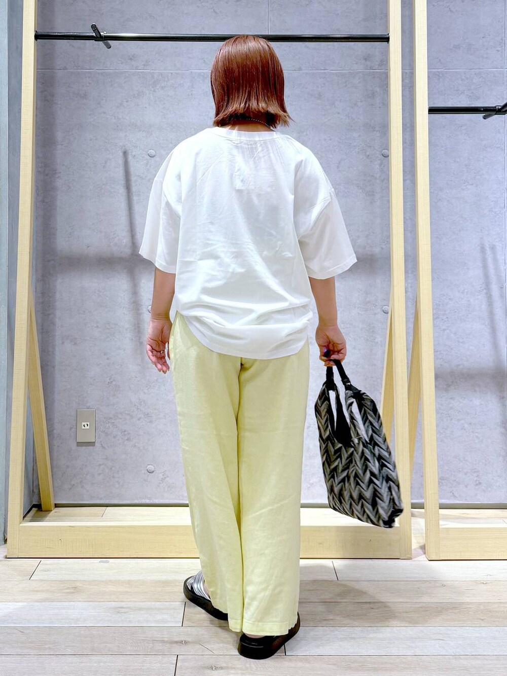 ブラック系のハンドバッグ、イエロー系のその他パンツ、シルバー系のサンダルを着用したレディースの夏コーディネートの4枚目の写真