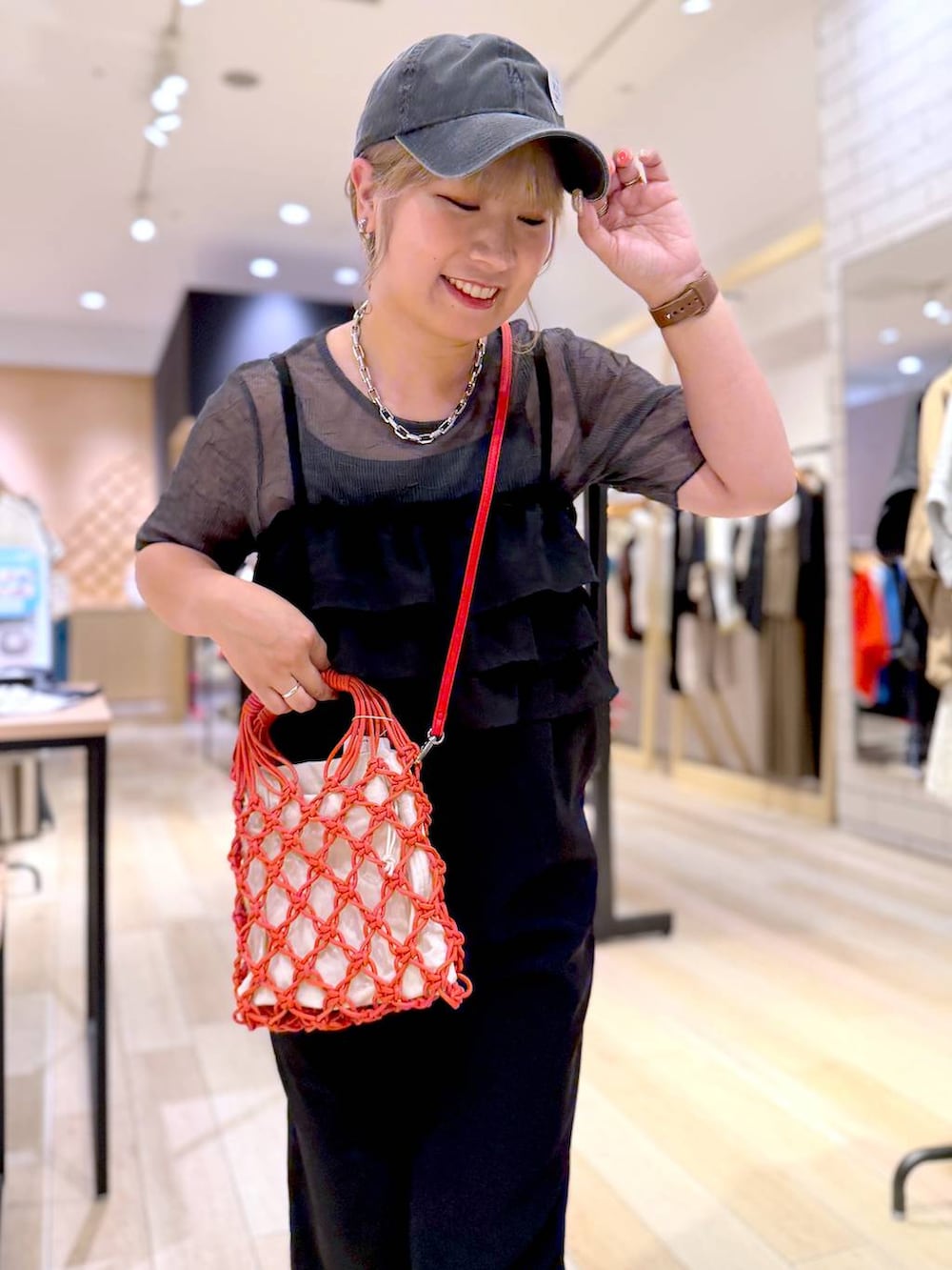 オレンジ系のハンドバッグ、ブラック系のサンダル、グレー系のTシャツ/カットソーを着用したレディースの夏コーディネートの2枚目の写真