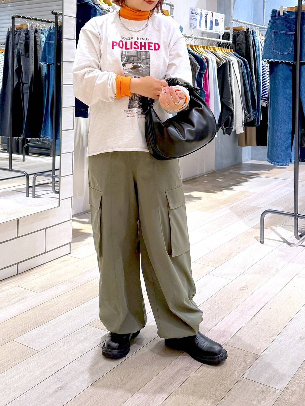 ブラック系のショルダーバッグ、オレンジ系のニット/セーター、グリーン系のカーゴパンツを着用したレディースの冬コーディネートの2枚目の写真