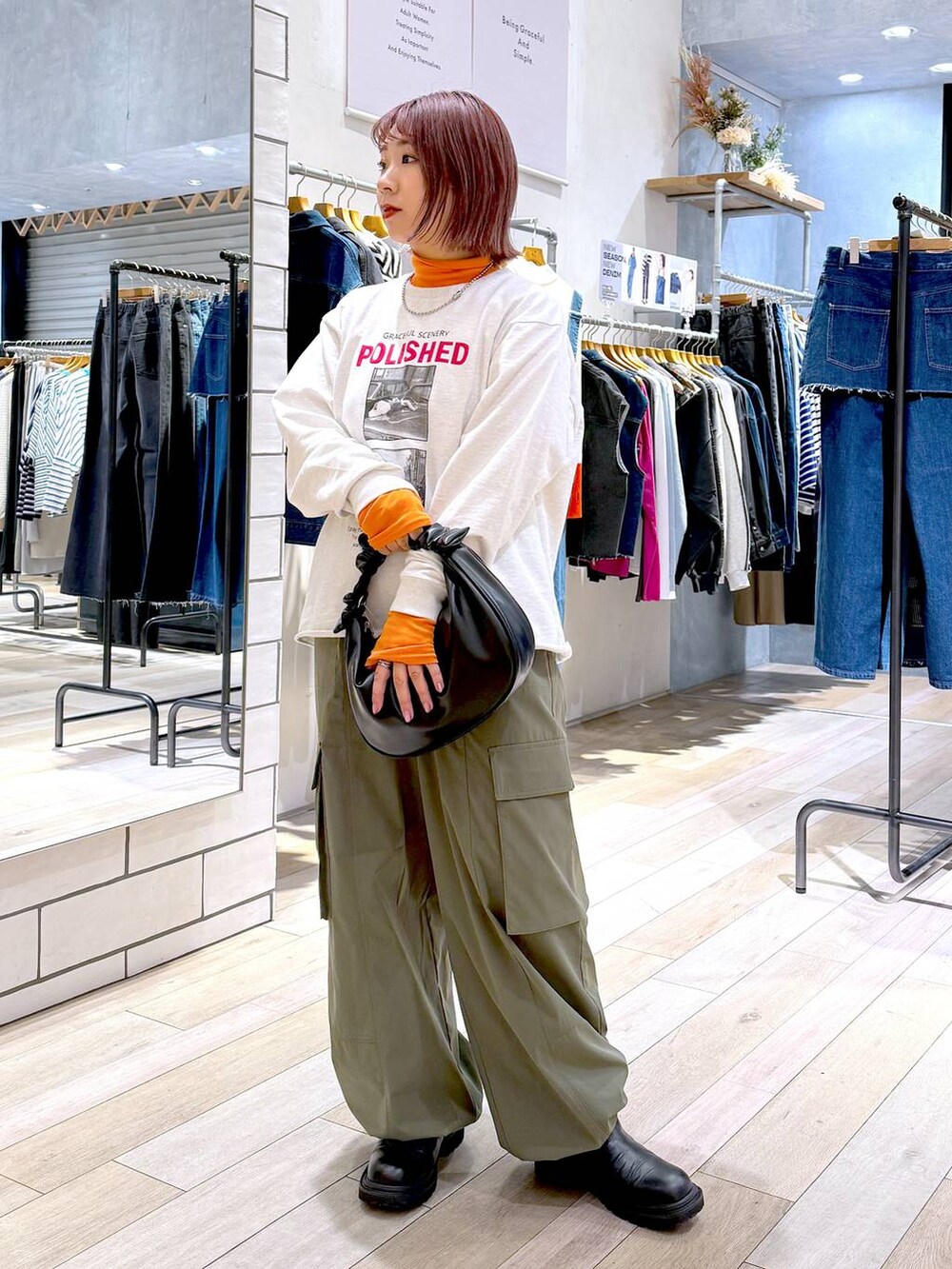 ブラック系のショルダーバッグ、オレンジ系のニット/セーター、グリーン系のカーゴパンツを着用したレディースの冬コーディネートの6枚目の写真