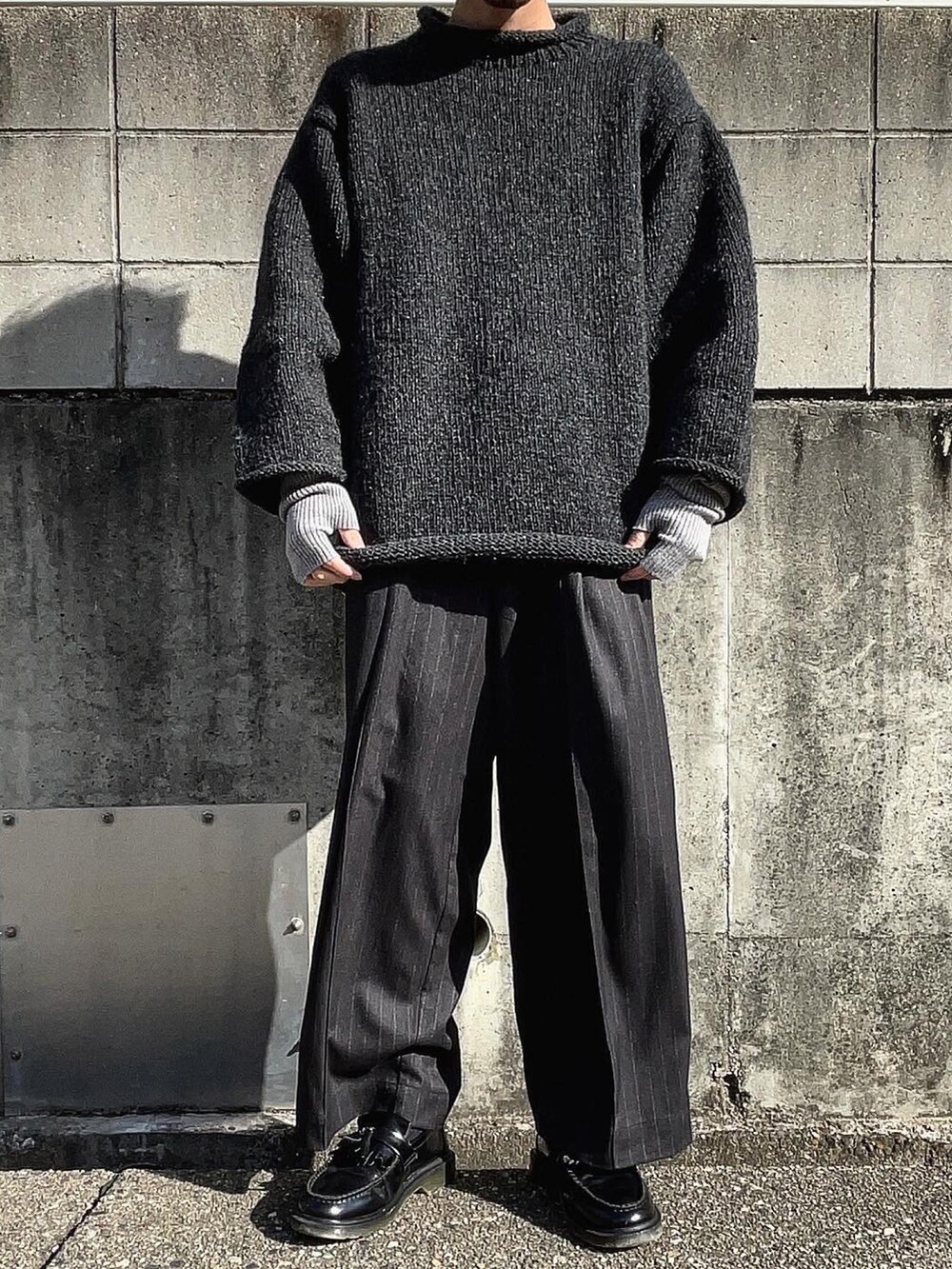 グレー系のニット/セーター、ブラック系のスラックス、ブラック系のローファーを着用したメンズの冬コーディネートの3枚目の写真