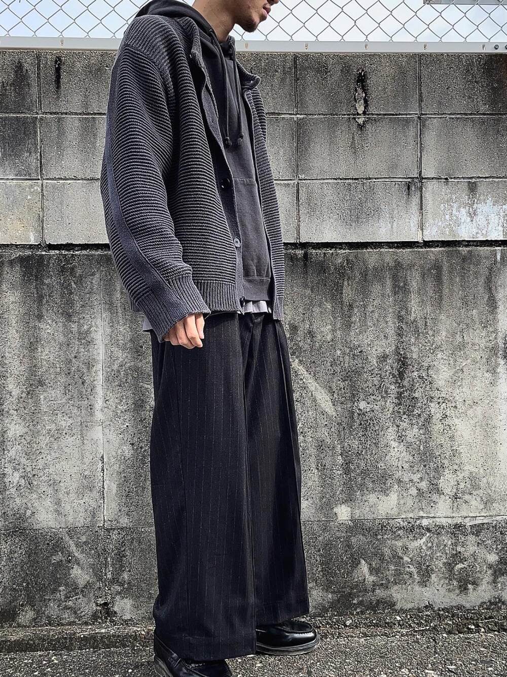 ブラック系のスラックス、ブラック系のカーディガン/ボレロ、グレー系のTシャツ/カットソーを着用したメンズの冬コーディネートの3枚目の写真