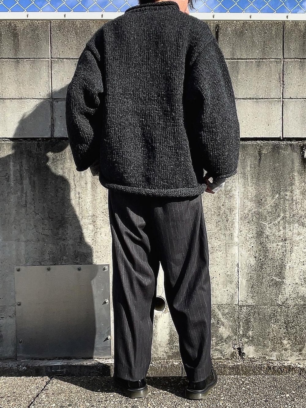 グレー系のニット/セーター、ブラック系のスラックス、ブラック系のローファーを着用したメンズの冬コーディネートの4枚目の写真