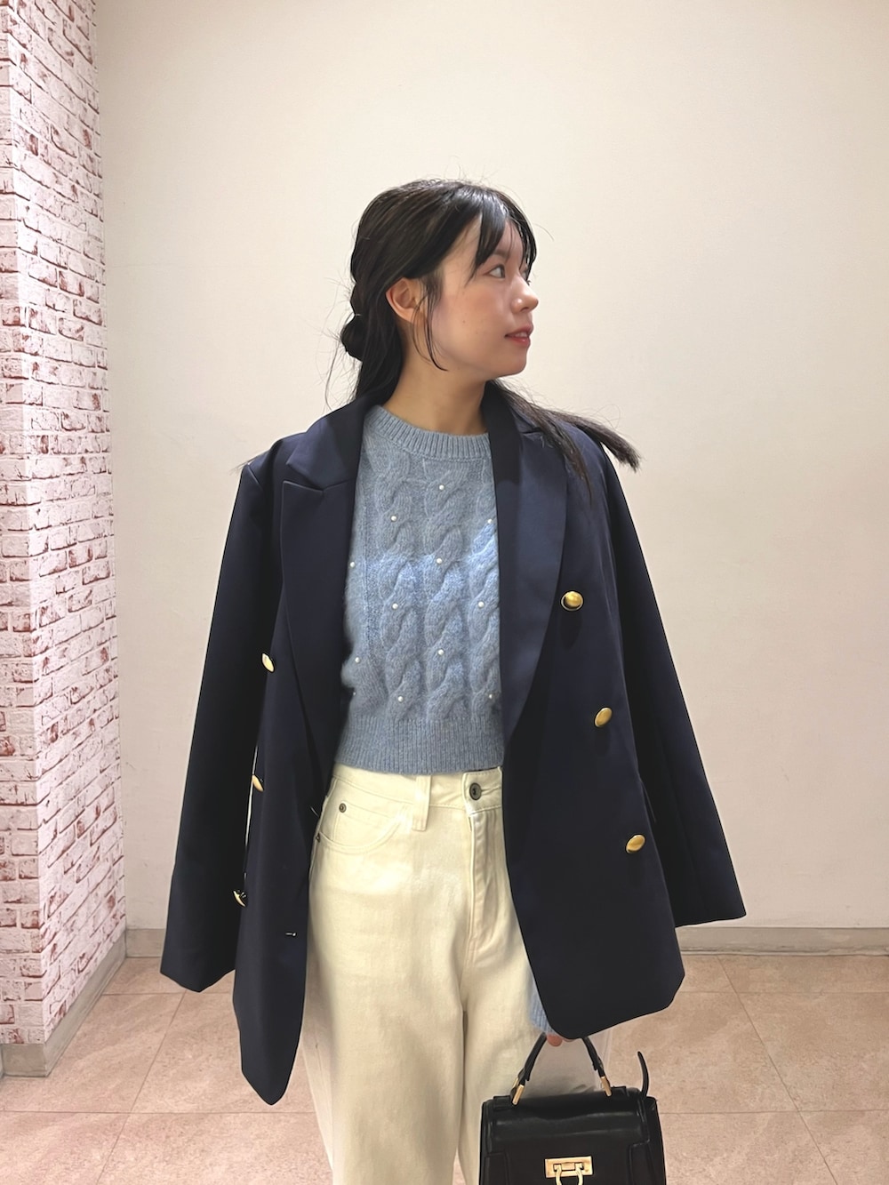 ブルー系のテーラードジャケット、ブルー系のニット/セーター、ホワイト系のデニムパンツを着用したレディースの冬コーディネートの2枚目の写真