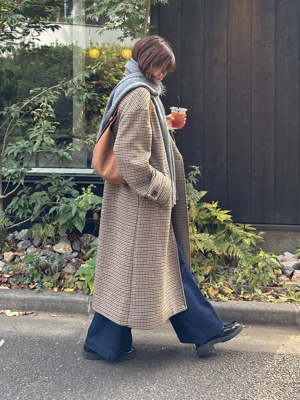 ベージュ系のチェスターコート、ブルー系のデニムパンツ、グレー系のストール/ショールを着用したレディースの秋コーディネートの2枚目の写真