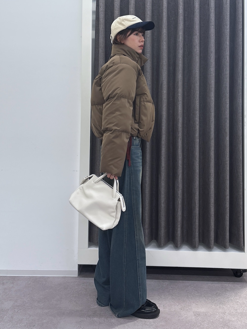 ブラック系のブルゾン、ブルー系のデニムパンツを着用したレディースの冬コーディネートの2枚目の写真