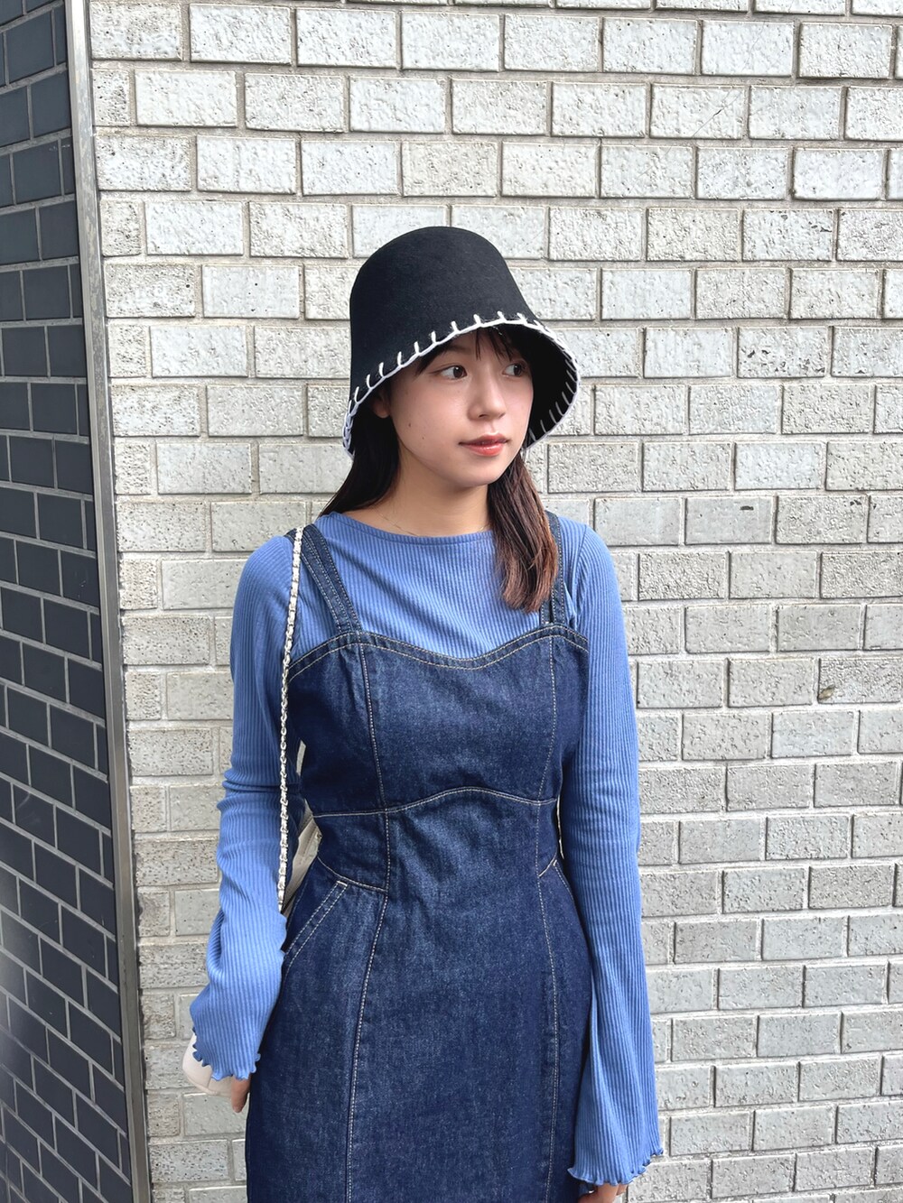 ブルー系のTシャツ/カットソー、ブルー系のジャンパースカート、ホワイト系のショルダーバッグを着用したレディースの秋コーディネートの2枚目の写真