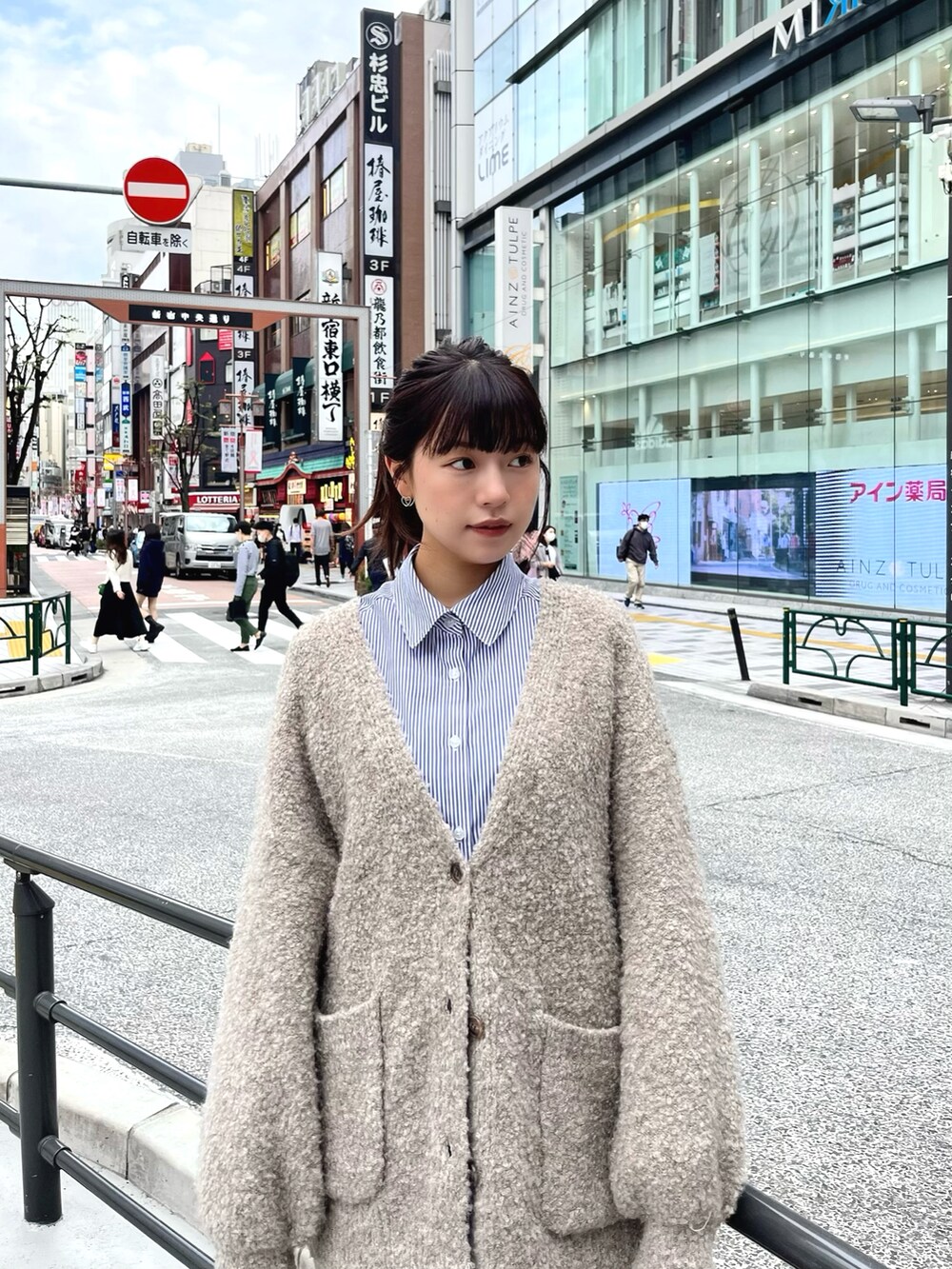 グレー系のカーディガン/ボレロ、ブルー系のシャツ/ブラウス、ホワイト系のスカートを着用したレディースの秋コーディネートの2枚目の写真