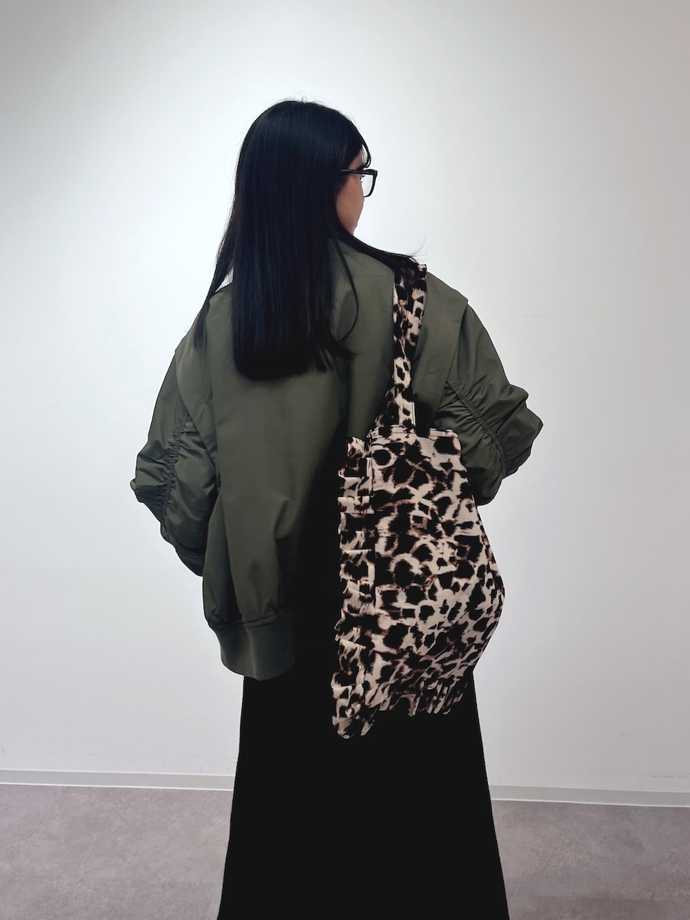 グリーン系のMA-1、ブラック系のワンピース、ブラック系のトートバッグを着用したレディースの冬コーディネートの3枚目の写真