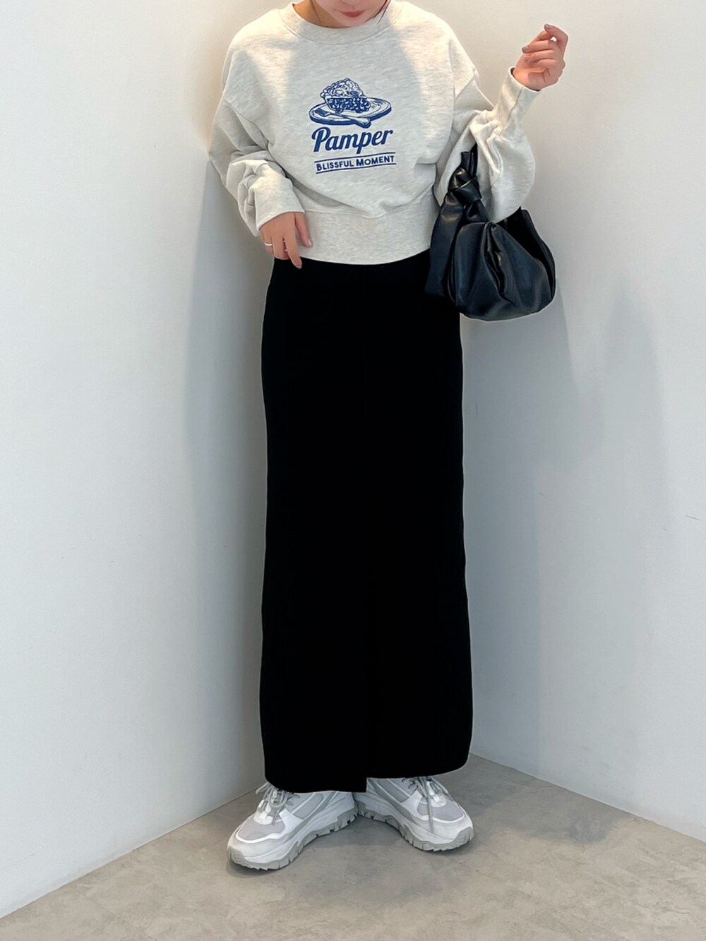 ホワイト系のTシャツ/カットソー、ブラック系のスカート、ホワイト系のスニーカーを着用したレディースの秋コーディネートの2枚目の写真