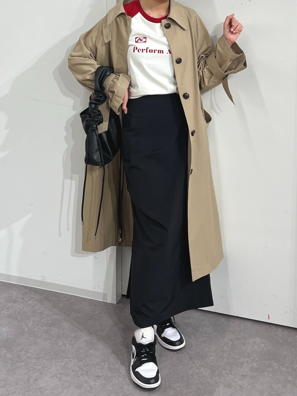 ベージュ系のトレンチコート、レッド系のTシャツ/カットソー、ブラック系のスカートを着用したレディースの春コーディネートの2枚目の写真