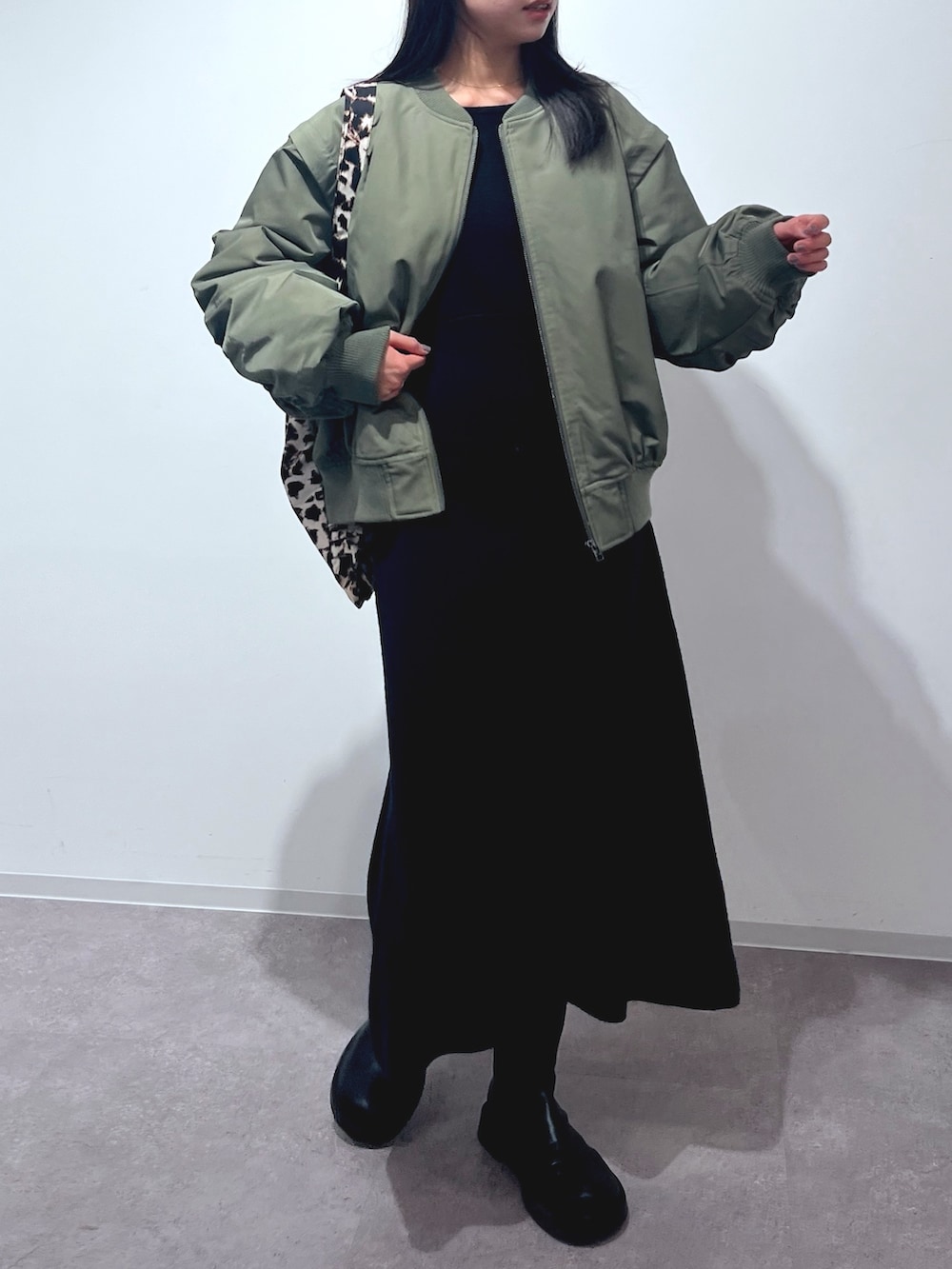 グリーン系のMA-1、ブラック系のワンピース、ブラック系のトートバッグを着用したレディースの冬コーディネートの2枚目の写真
