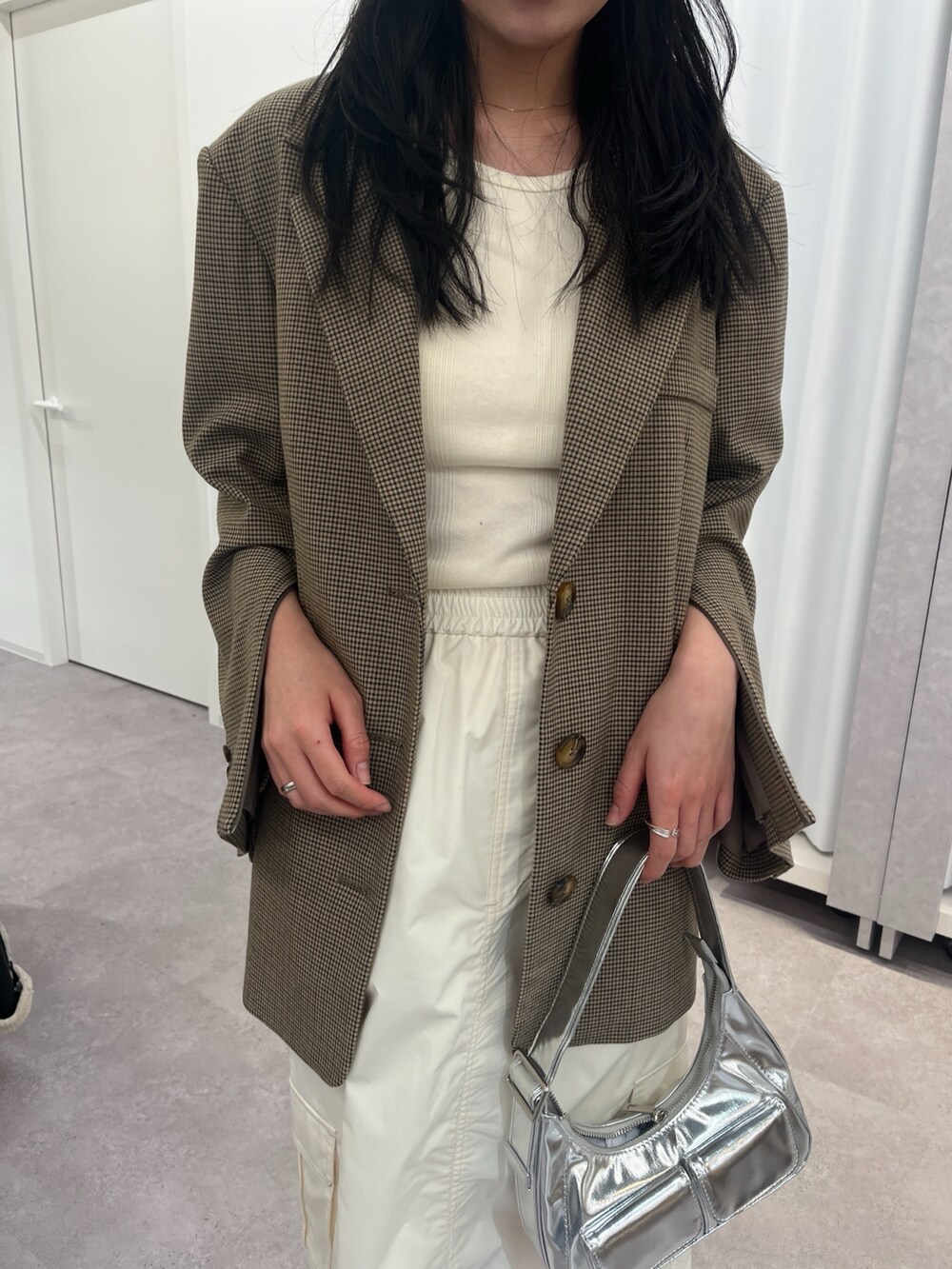 ブラウン系のテーラードジャケット、ブラック系のスカート、ホワイト系のスニーカーを着用したレディースの冬コーディネートの4枚目の写真