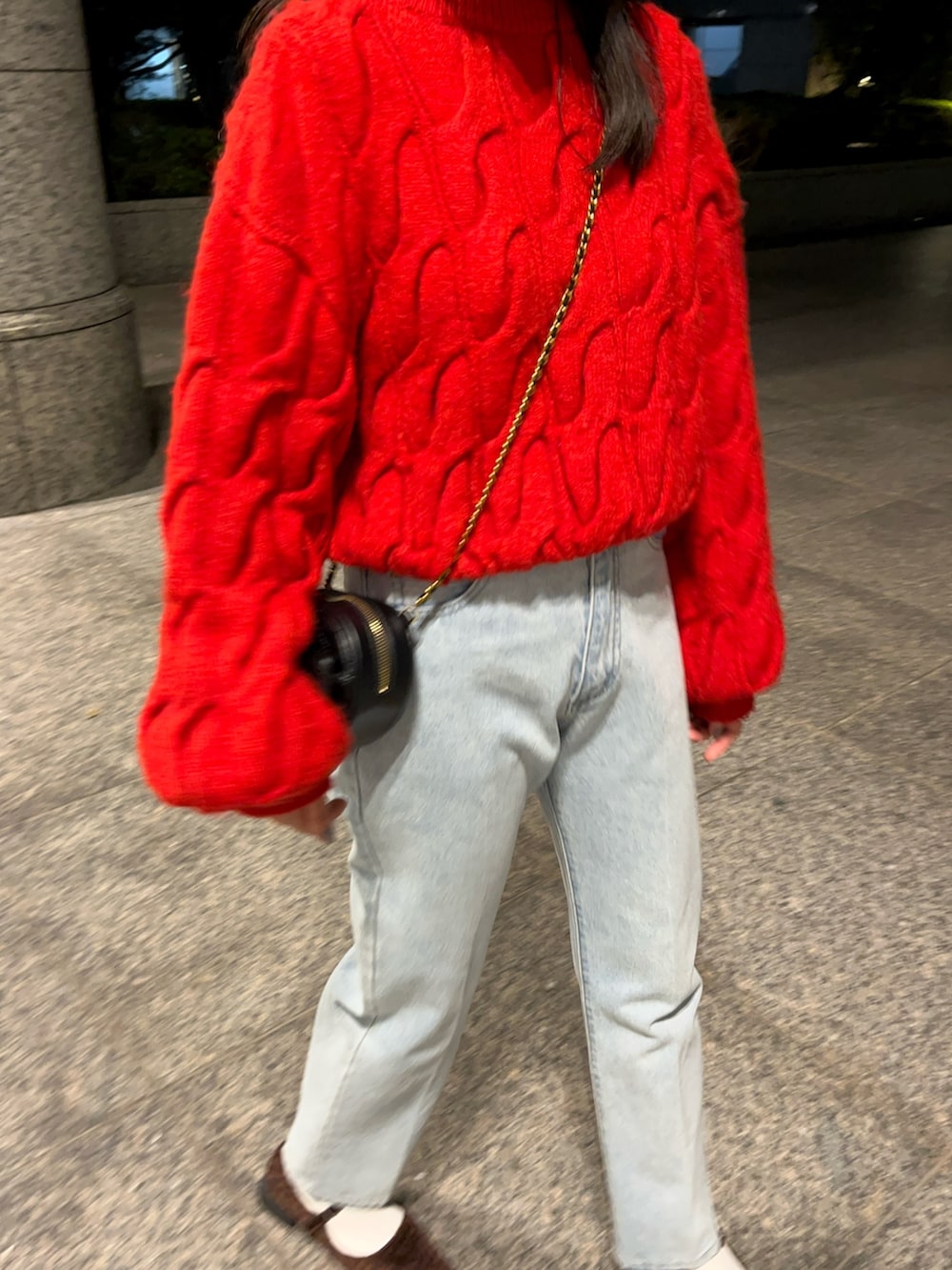 レッド系のニット/セーター、ブルー系のデニムパンツ、ブラック系のショルダーバッグを着用したレディースの秋コーディネートの3枚目の写真