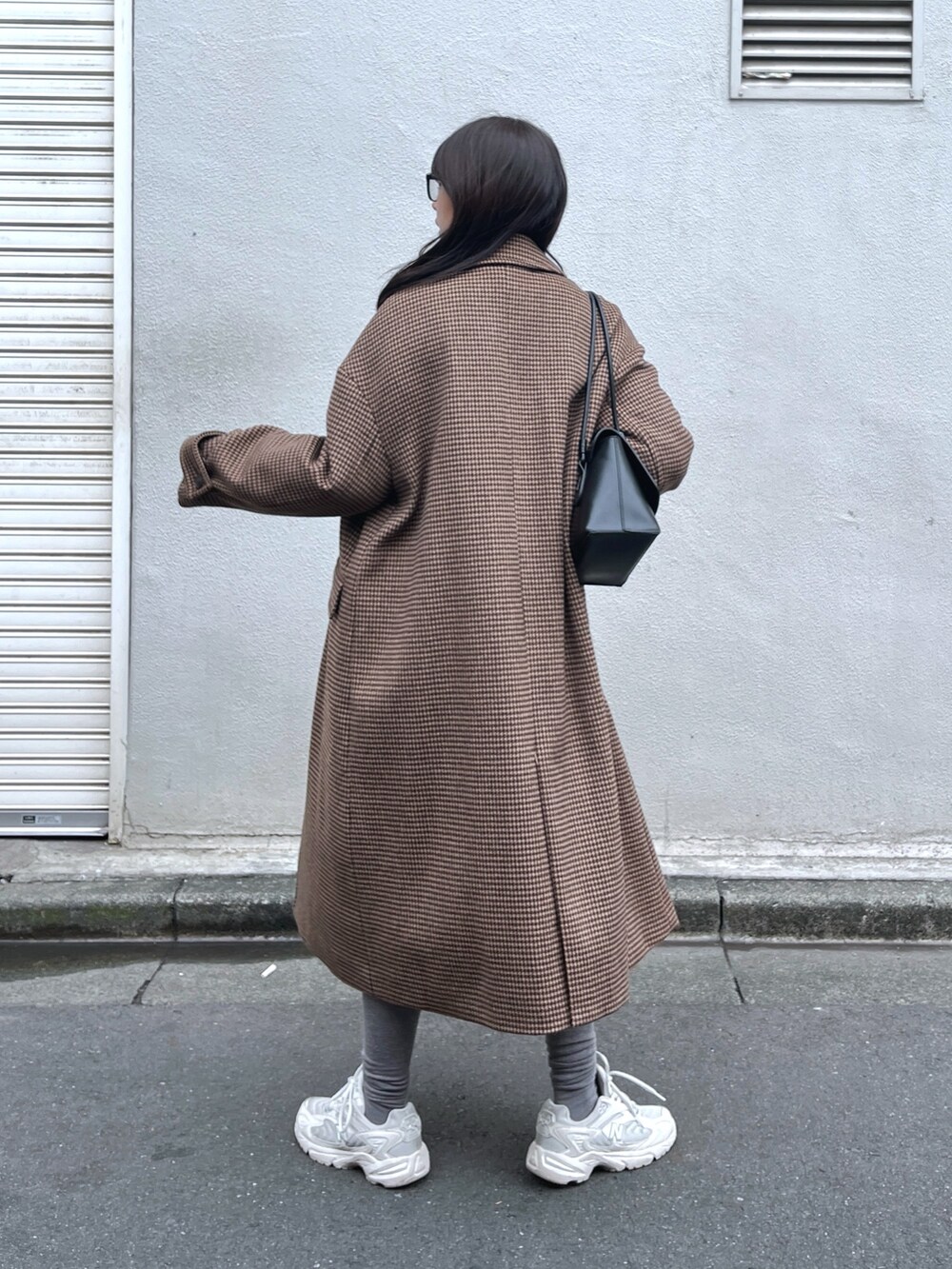 ブラウン系のチェスターコート、ホワイト系のニット/セーター、ブラック系のその他パンツを着用したレディースの冬コーディネートの3枚目の写真