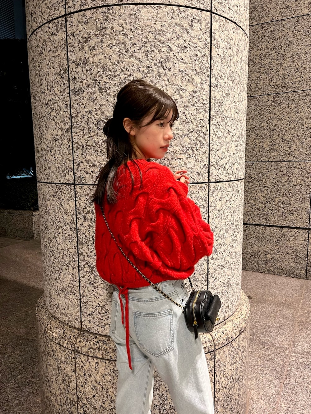 レッド系のニット/セーター、ブルー系のデニムパンツ、ブラック系のショルダーバッグを着用したレディースの秋コーディネートの2枚目の写真