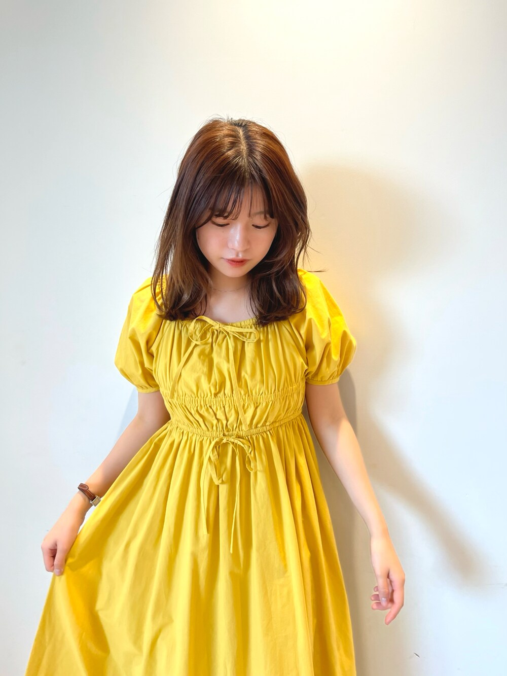 イエロー系のワンピース、ホワイト系のサンダルを着用したレディースの夏コーディネートの2枚目の写真