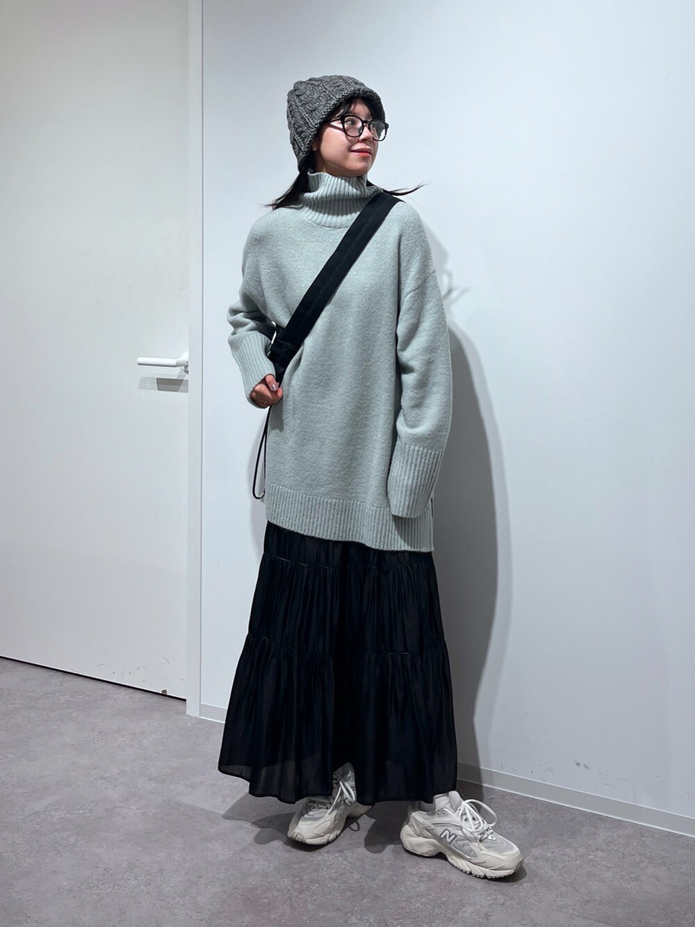 グリーン系のニット/セーター、ブラック系のスカート、ホワイト系のスニーカーを着用したレディースの冬コーディネートの2枚目の写真
