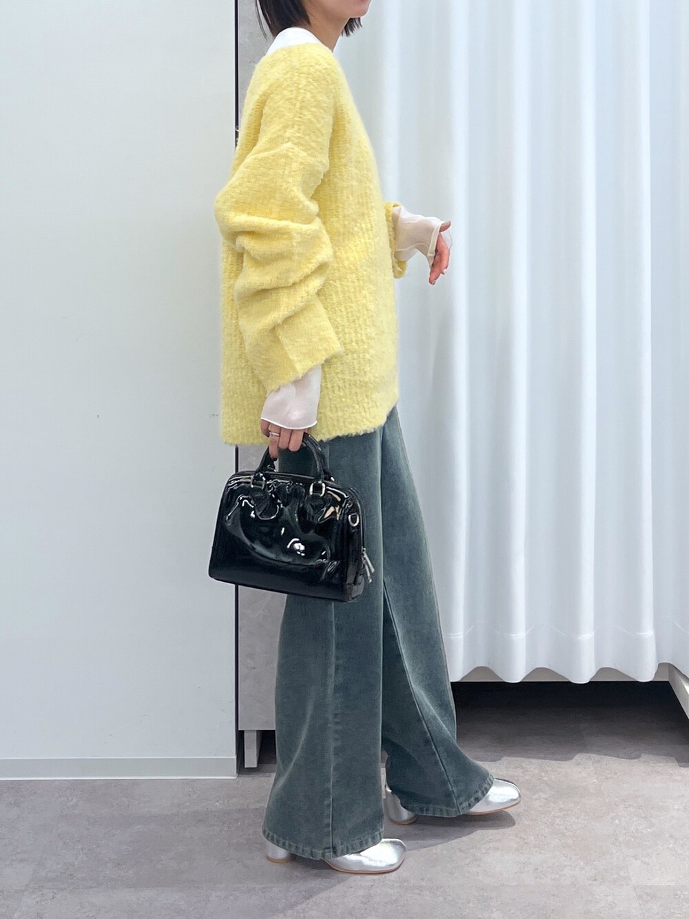 イエロー系のニット/セーター、ホワイト系のTシャツ/カットソー、ブルー系のデニムパンツを着用したレディースの冬コーディネートの2枚目の写真