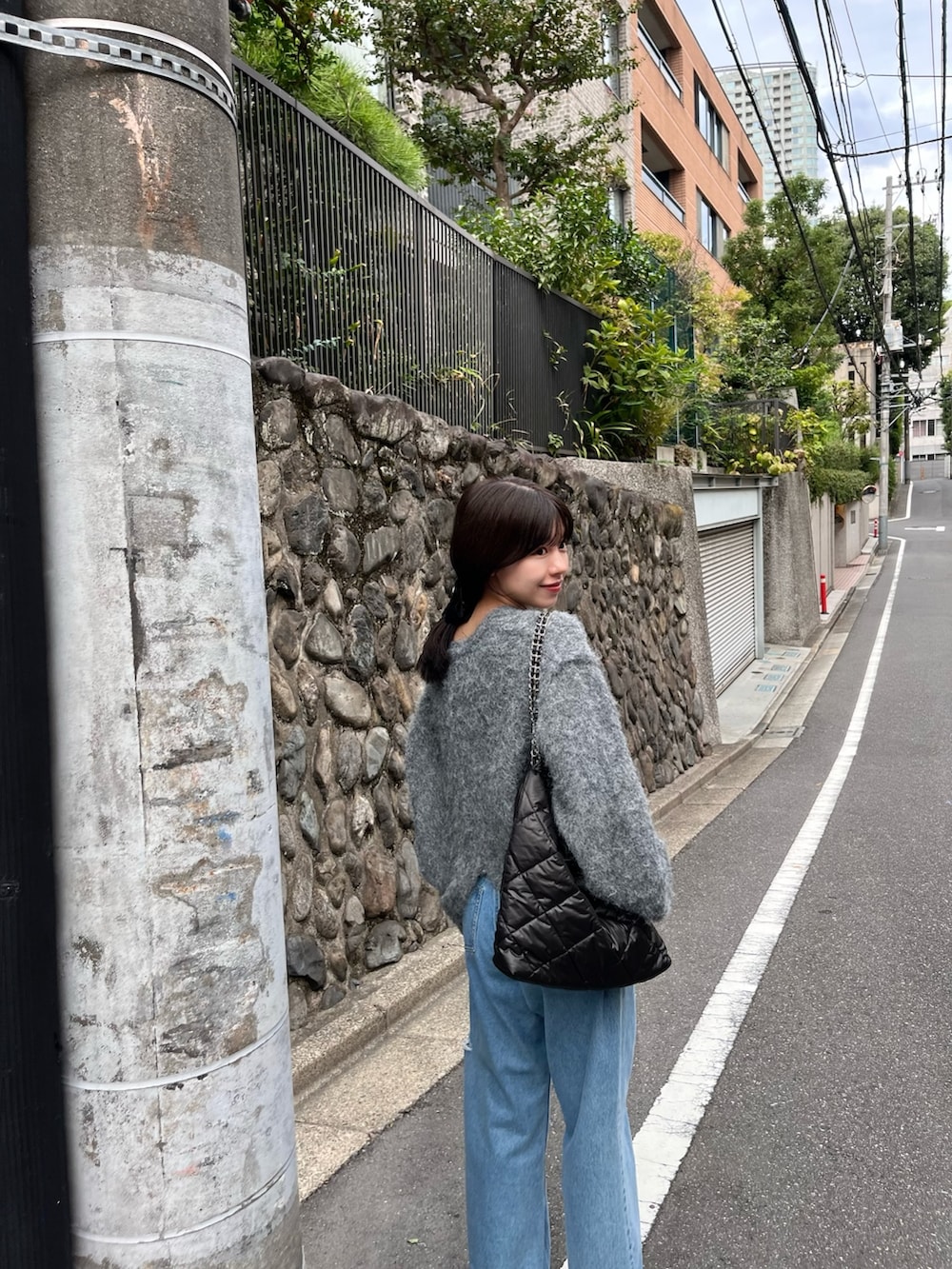 グレー系のニット/セーター、ブルー系のデニムパンツ、ブラウン系のバレエシューズを着用したレディースの秋コーディネートの3枚目の写真