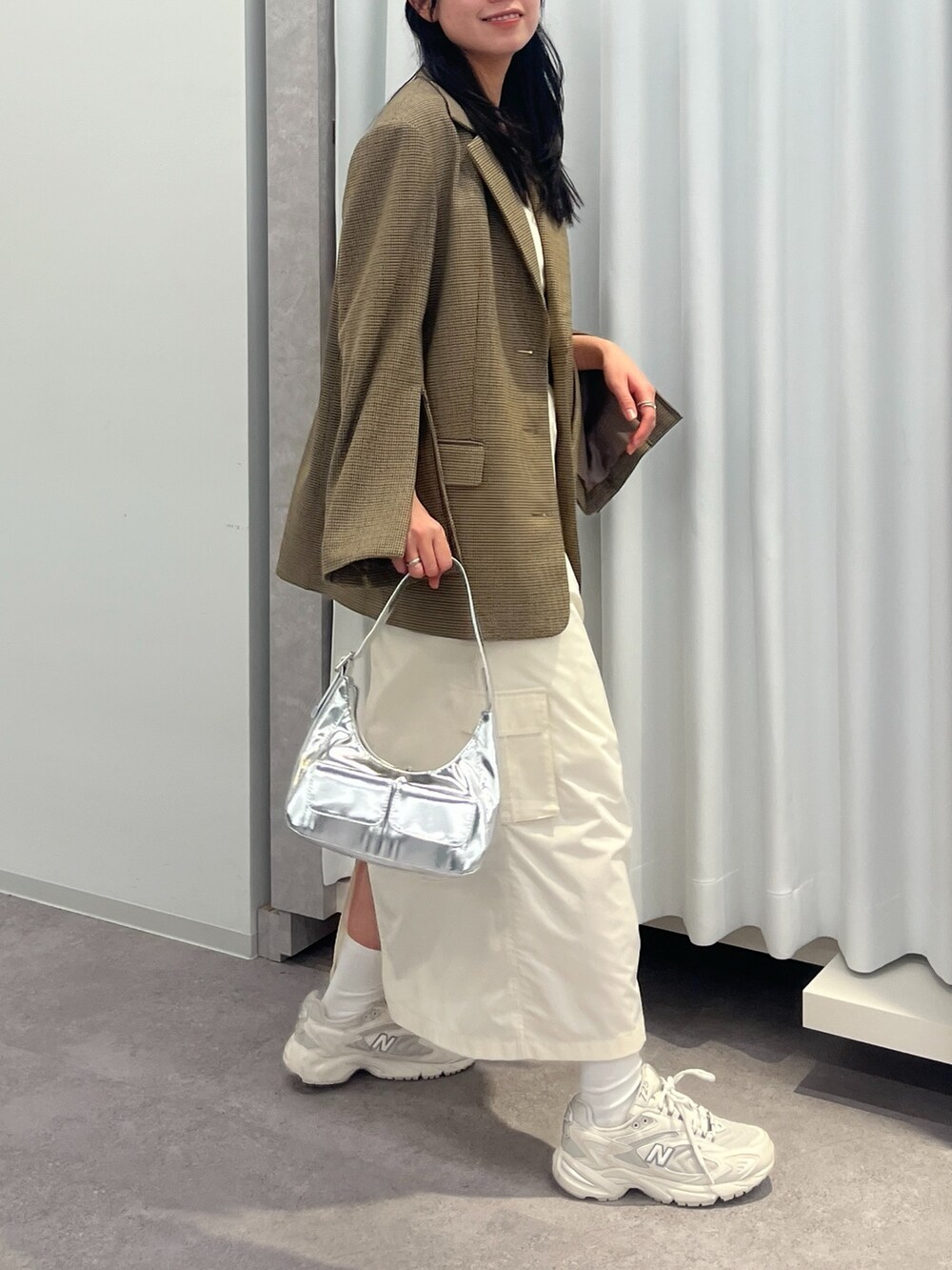 ブラウン系のテーラードジャケット、ブラック系のスカート、ホワイト系のスニーカーを着用したレディースの冬コーディネートの2枚目の写真