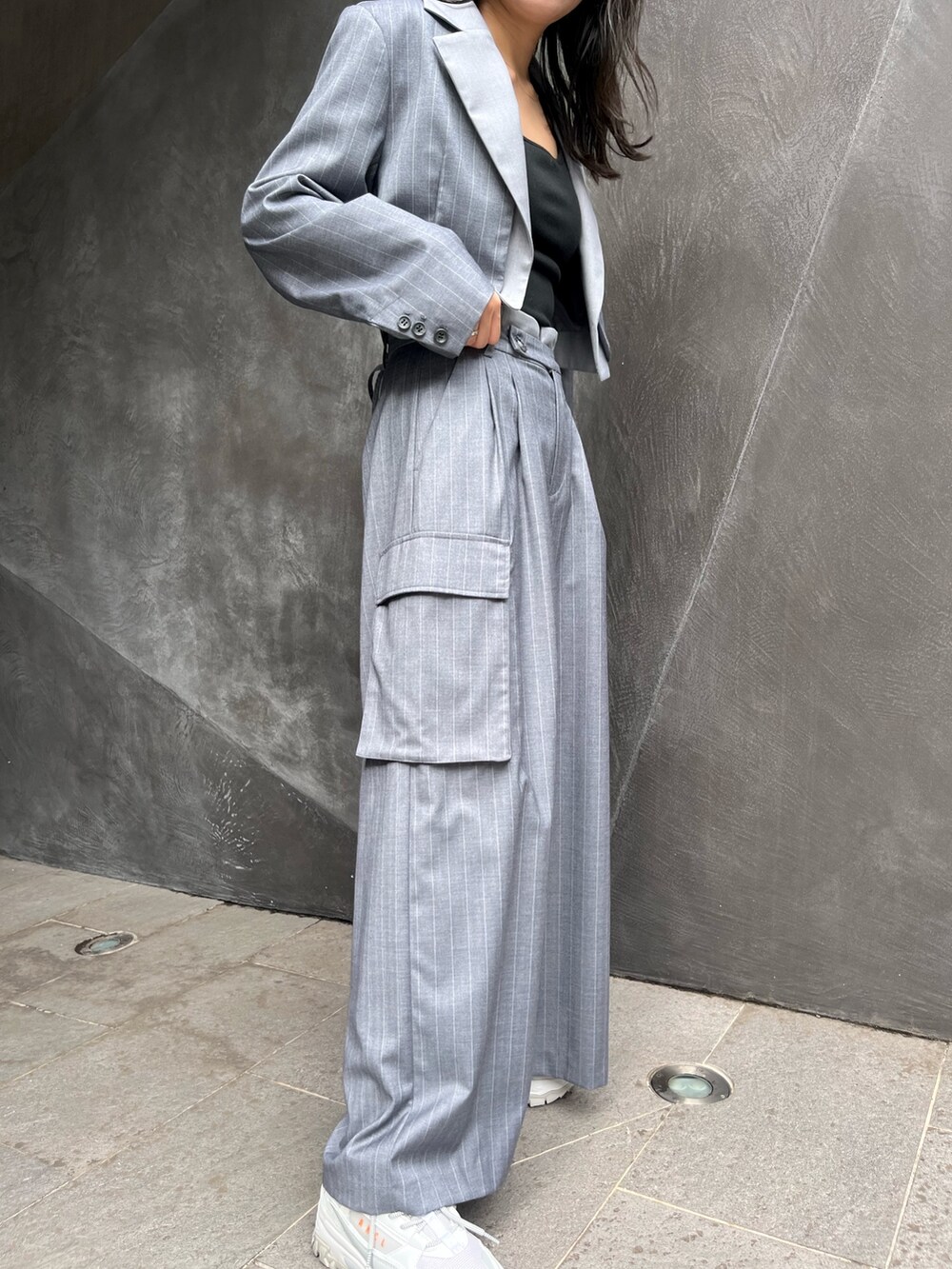 グレー系のテーラードジャケット、グレー系のスラックス、ホワイト系のスニーカーを着用したレディースの秋コーディネートの4枚目の写真