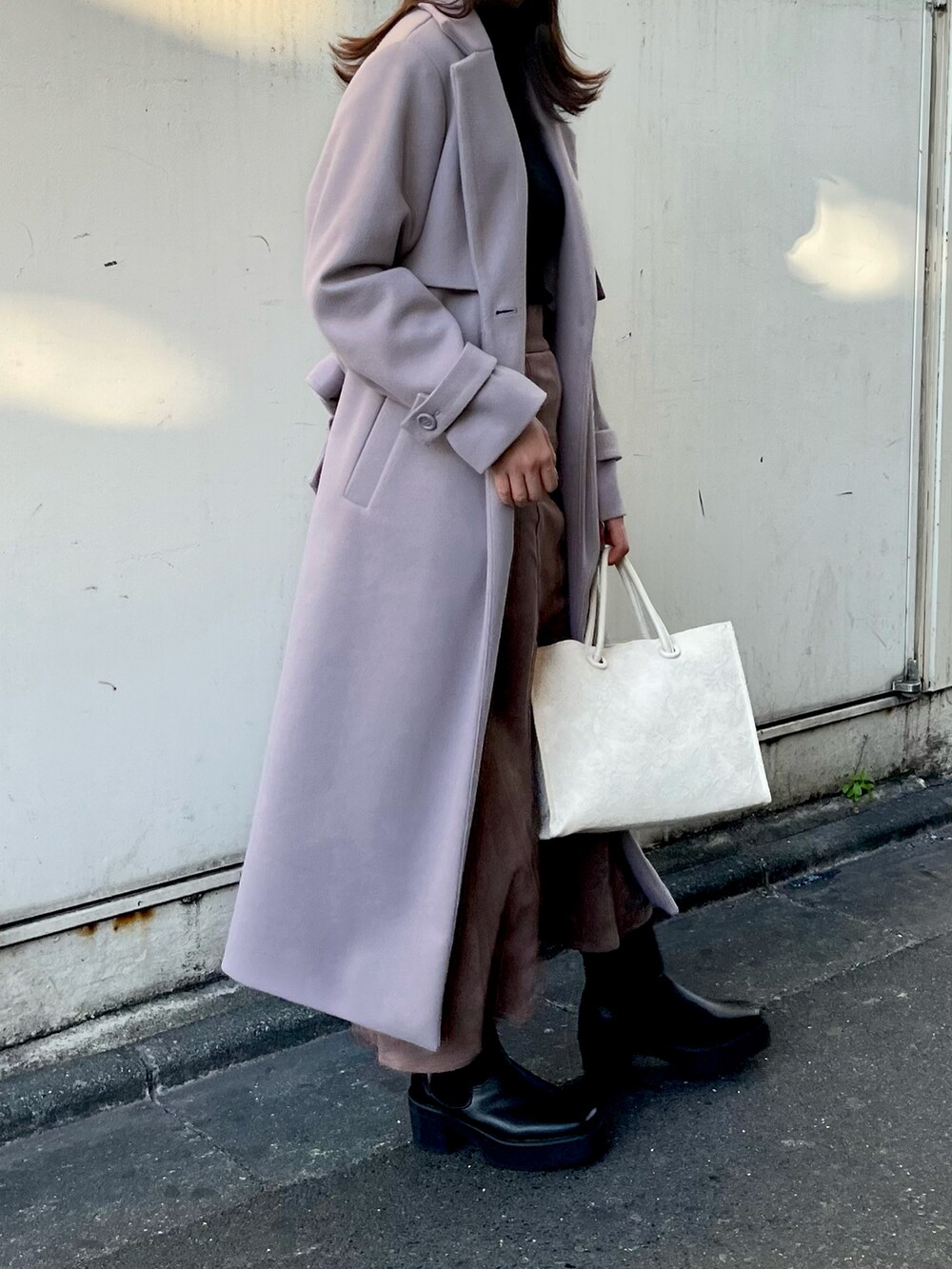 ブラック系のニット/セーター、パープル系のチェスターコート、ブラウン系のスカートを着用したレディースの秋コーディネートの3枚目の写真