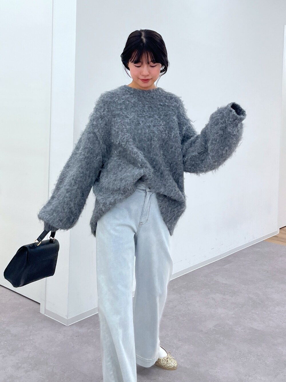 グレー系のニット/セーター、ブルー系のデニムパンツ、ブラック系のショルダーバッグを着用したレディースの冬コーディネートの4枚目の写真