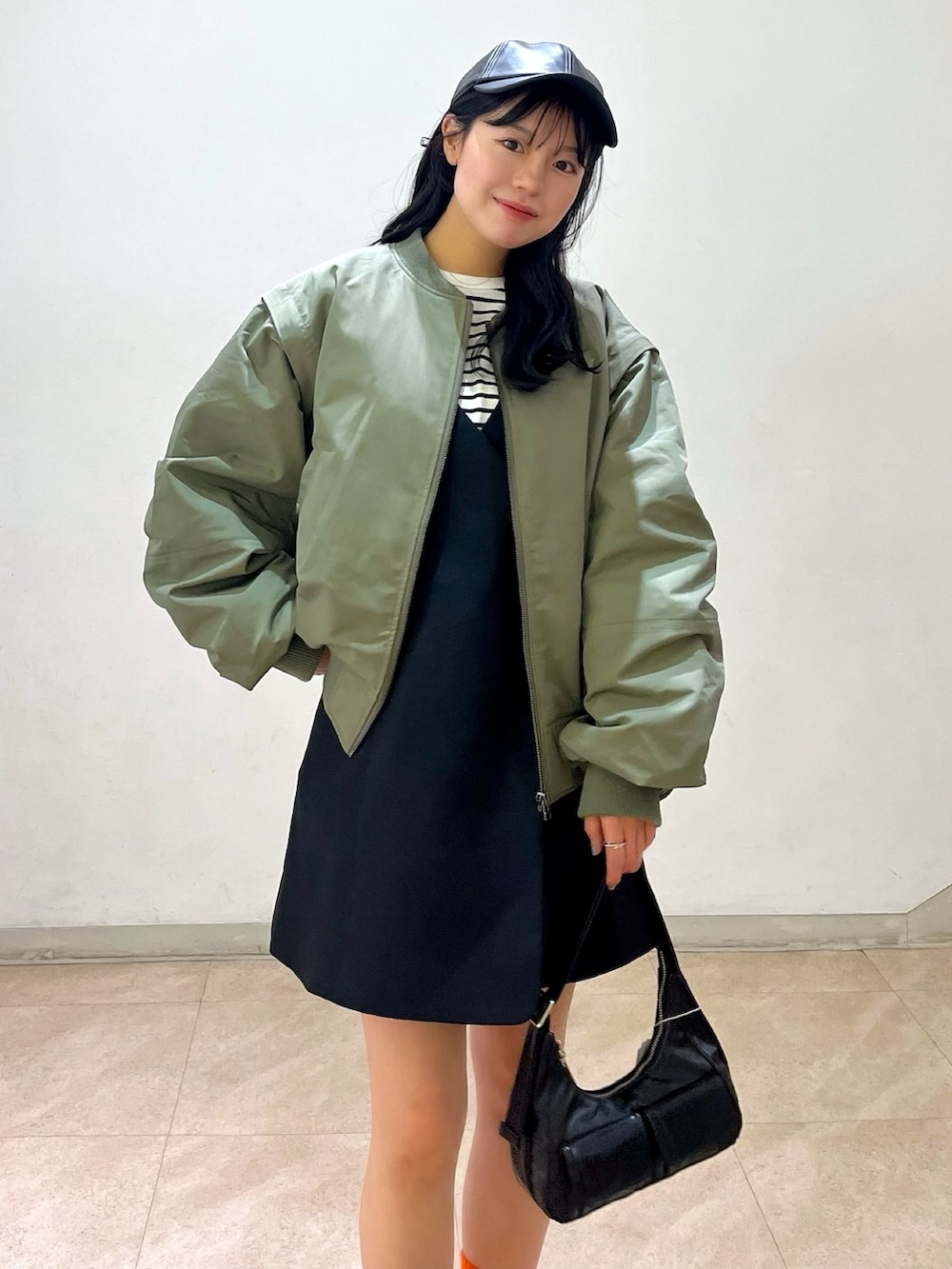 グリーン系のMA-1、ブラック系のワンピース、ブラック系のショルダーバッグを着用したレディースの冬コーディネートの2枚目の写真