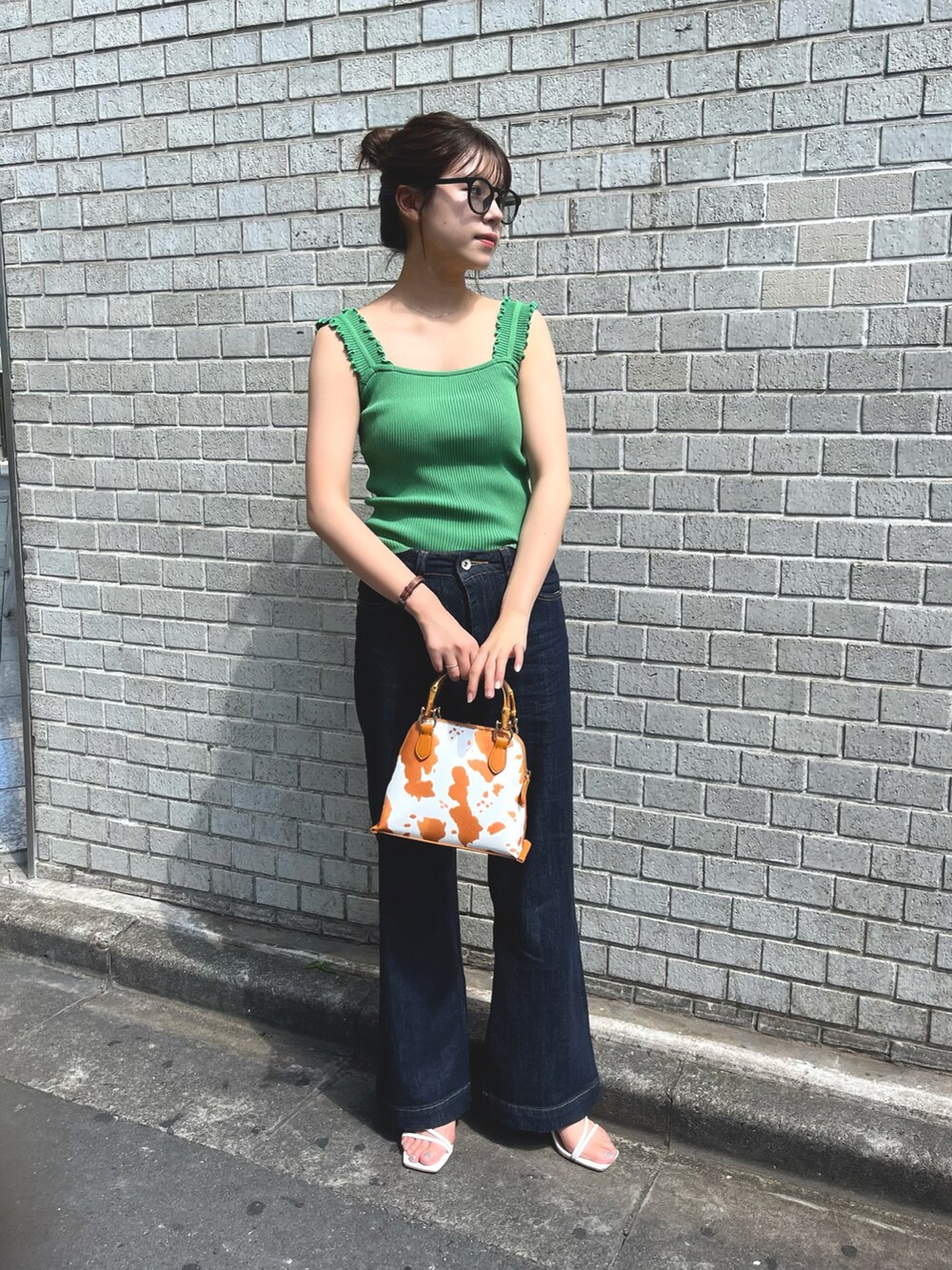 ブラック系のニット/セーター、ホワイト系のデニムパンツ、ブラウン系のショルダーバッグを着用したレディースの夏コーディネートの3枚目の写真