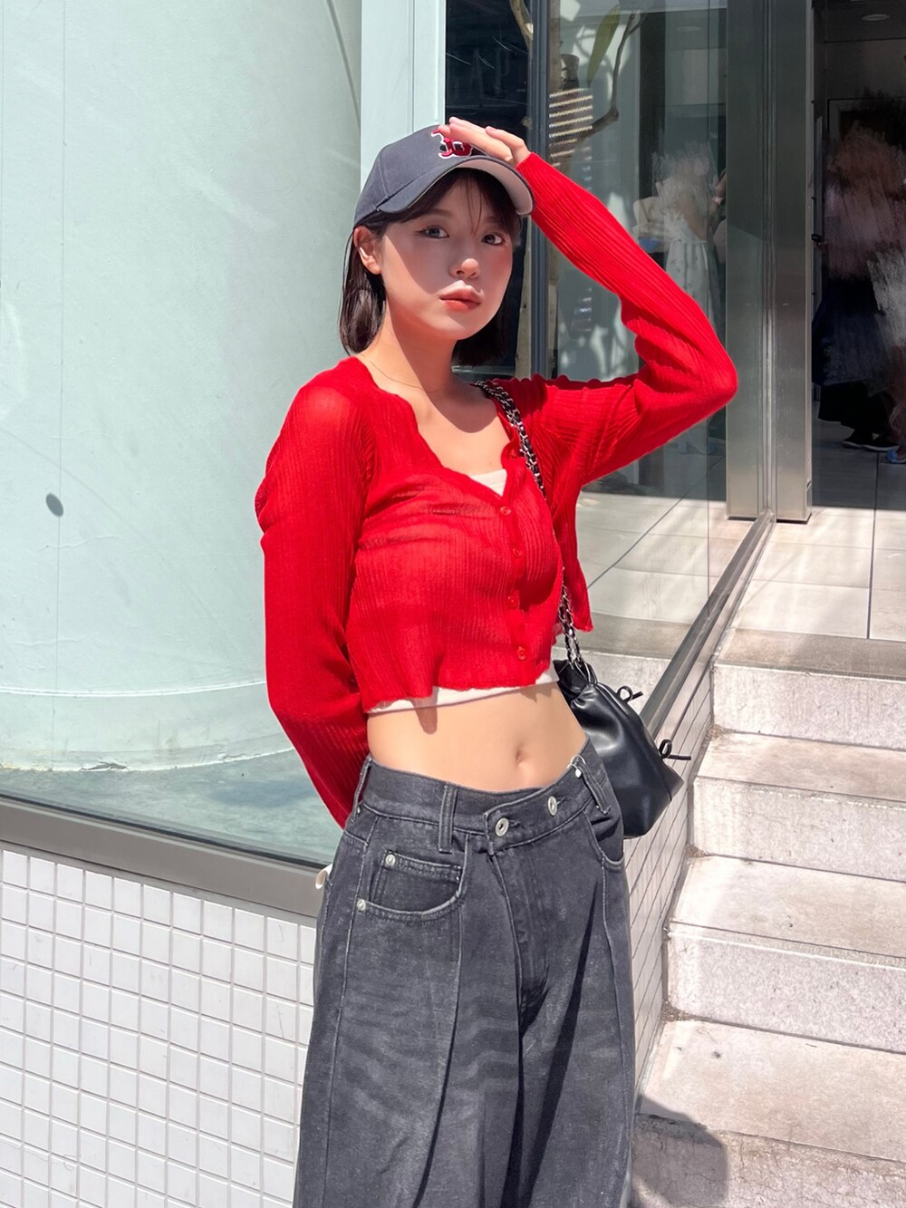 レッド系のカーディガン/ボレロ、ブルー系のデニムパンツを着用したレディースの秋コーディネートの3枚目の写真