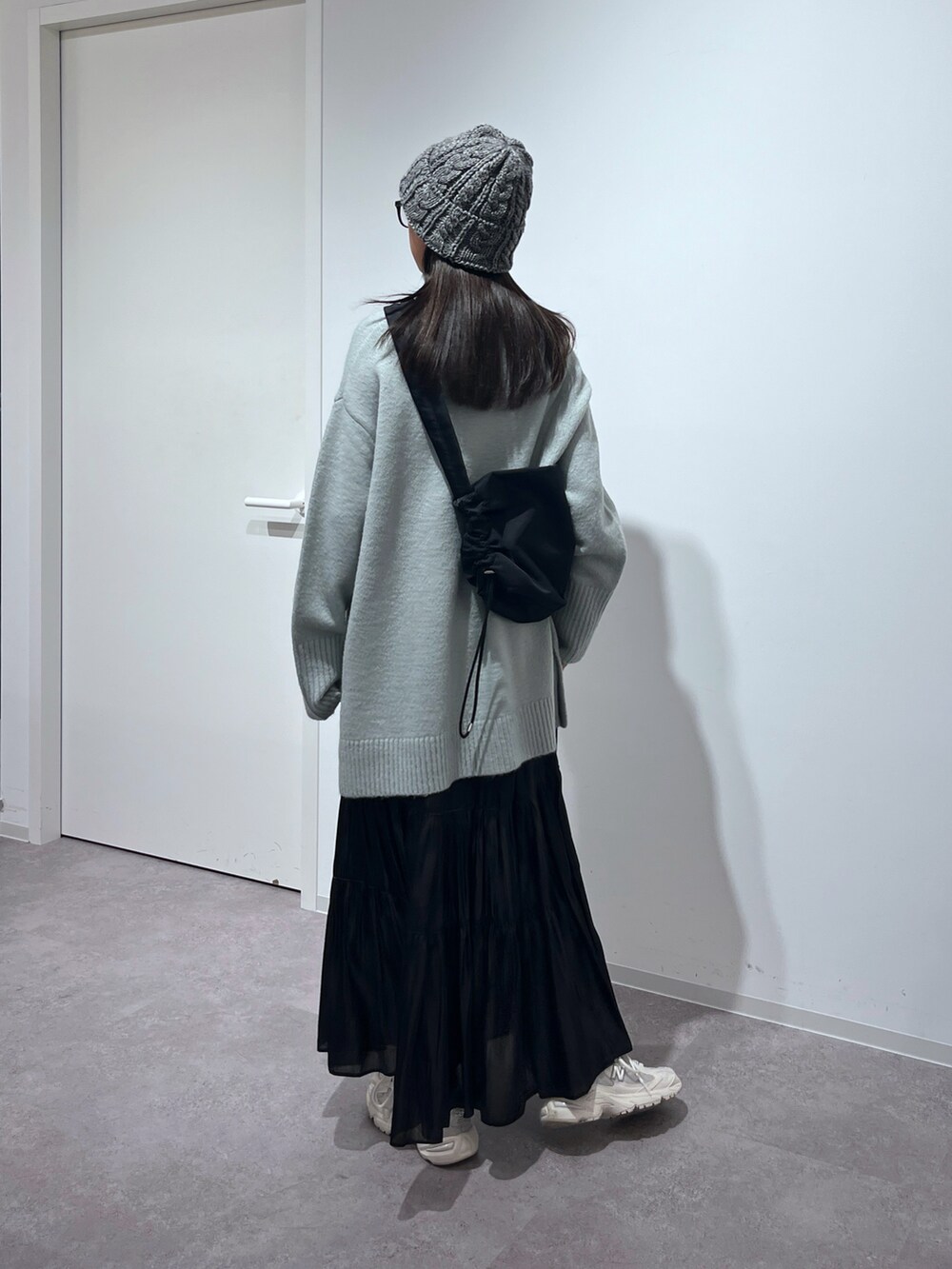 グリーン系のニット/セーター、ブラック系のスカート、ホワイト系のスニーカーを着用したレディースの冬コーディネートの3枚目の写真